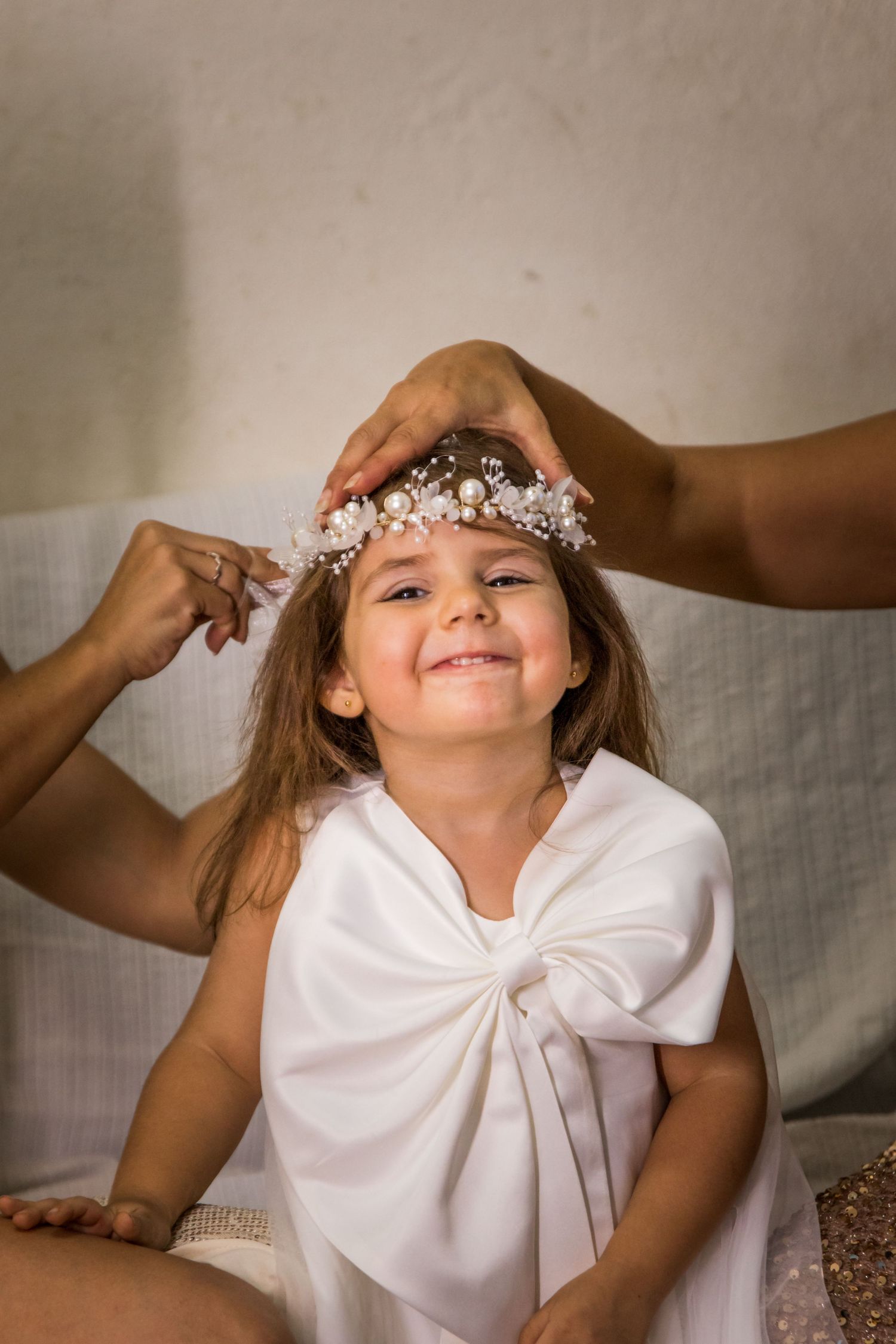 Child wearing white dress and floral crown in indoor portrait session.