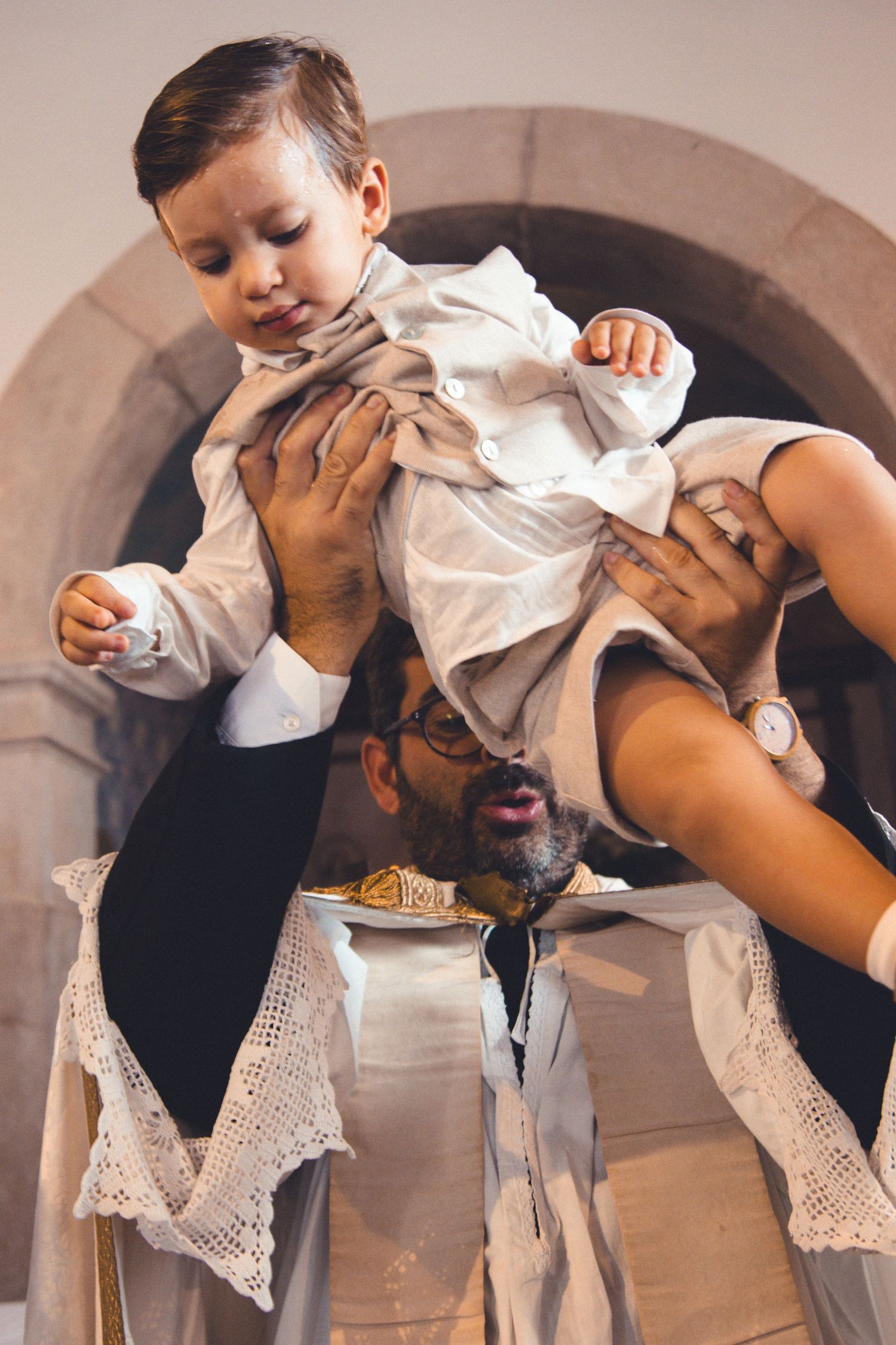 A playful moment during a baptism ceremony as a child is lifted up.