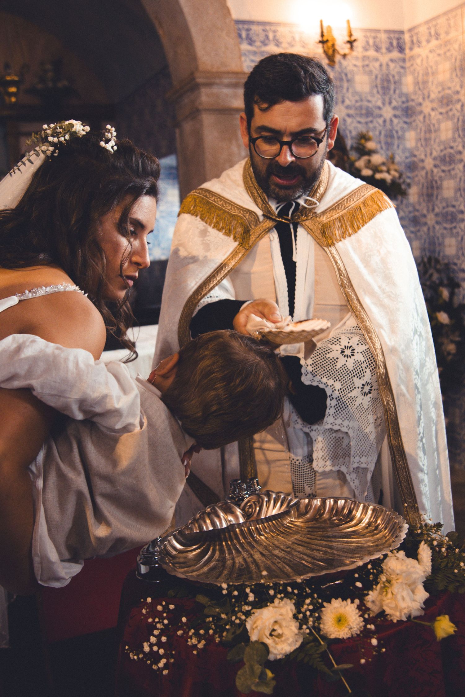 A religious ceremony takes place with clergy and participants gathered around a decorated silver basin.
