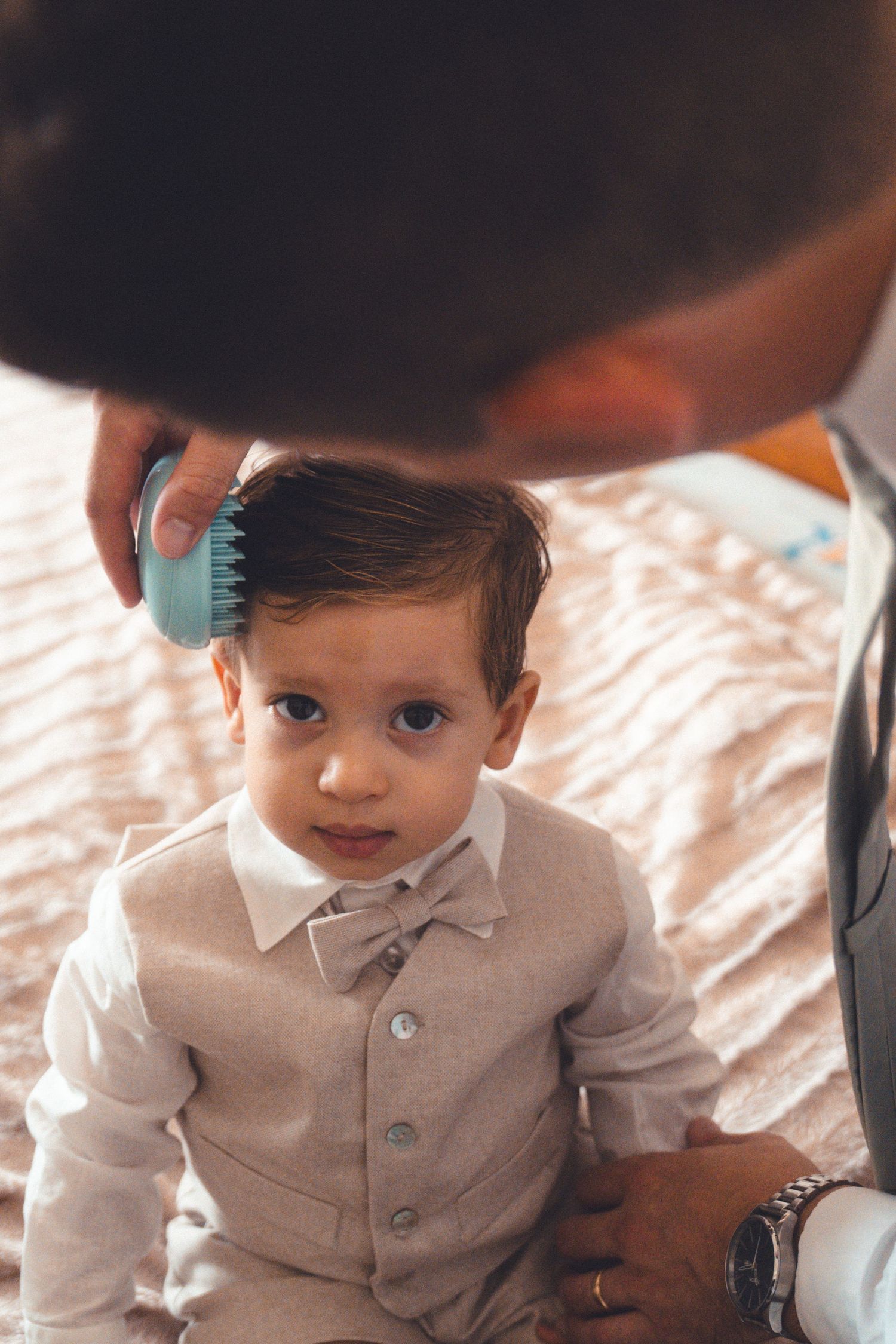 Young child in a light colored suit smiles sweetly at the camera.