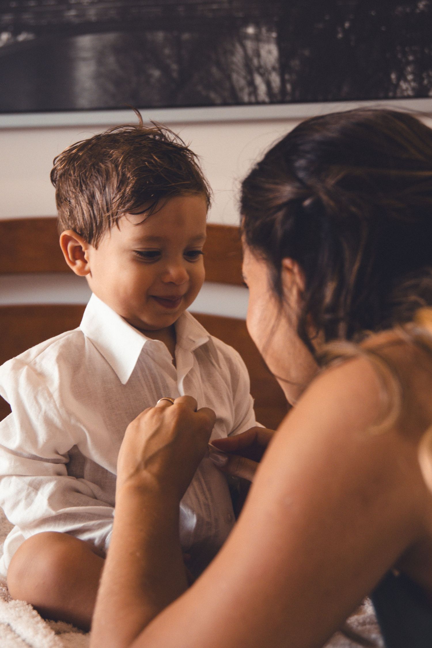 A tender moment between a child in a white shirt and caregiver during a special occasion preparation.