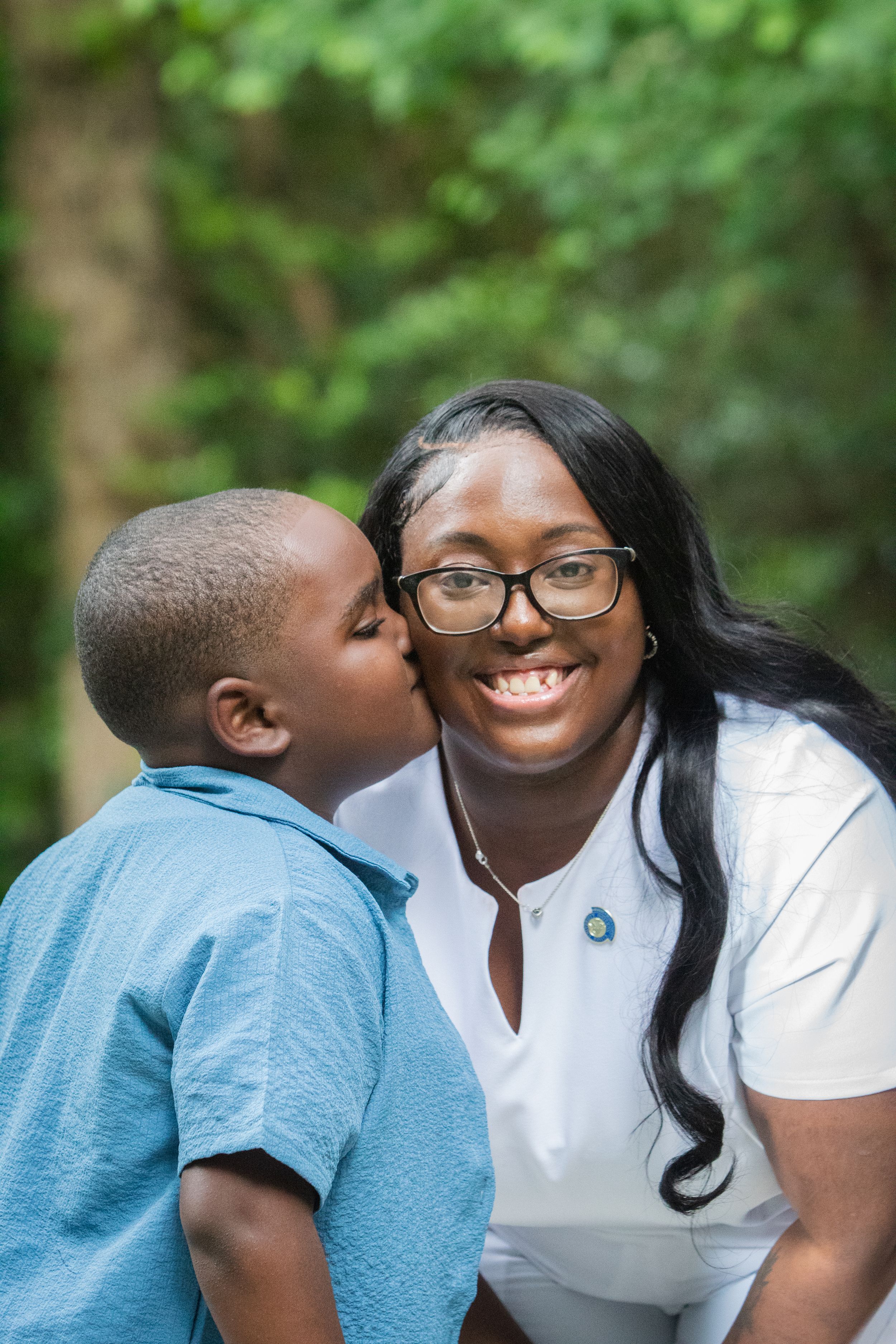 Sweet moment captured between parent and child outdoors with natural green background.