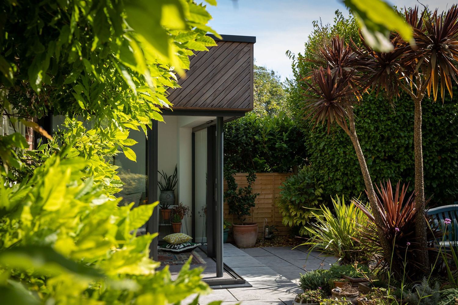 Tropical garden landscaping featuring palm trees and lush greenery around a modern extension.