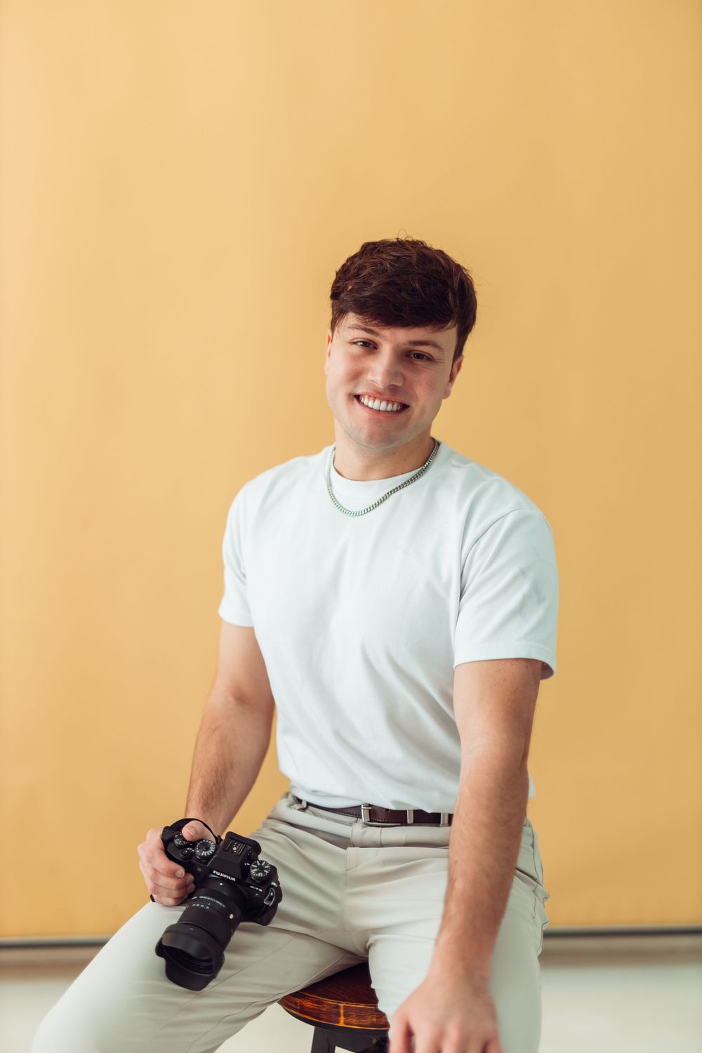 Portrait of Dallas Photographer, Eric Aaberg, sitting down with a white t-shirt holding a camera.