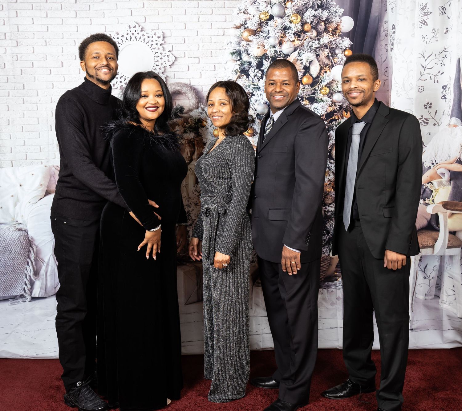 Formal family portrait with five people wearing elegant black and gray attire against white backdrop.