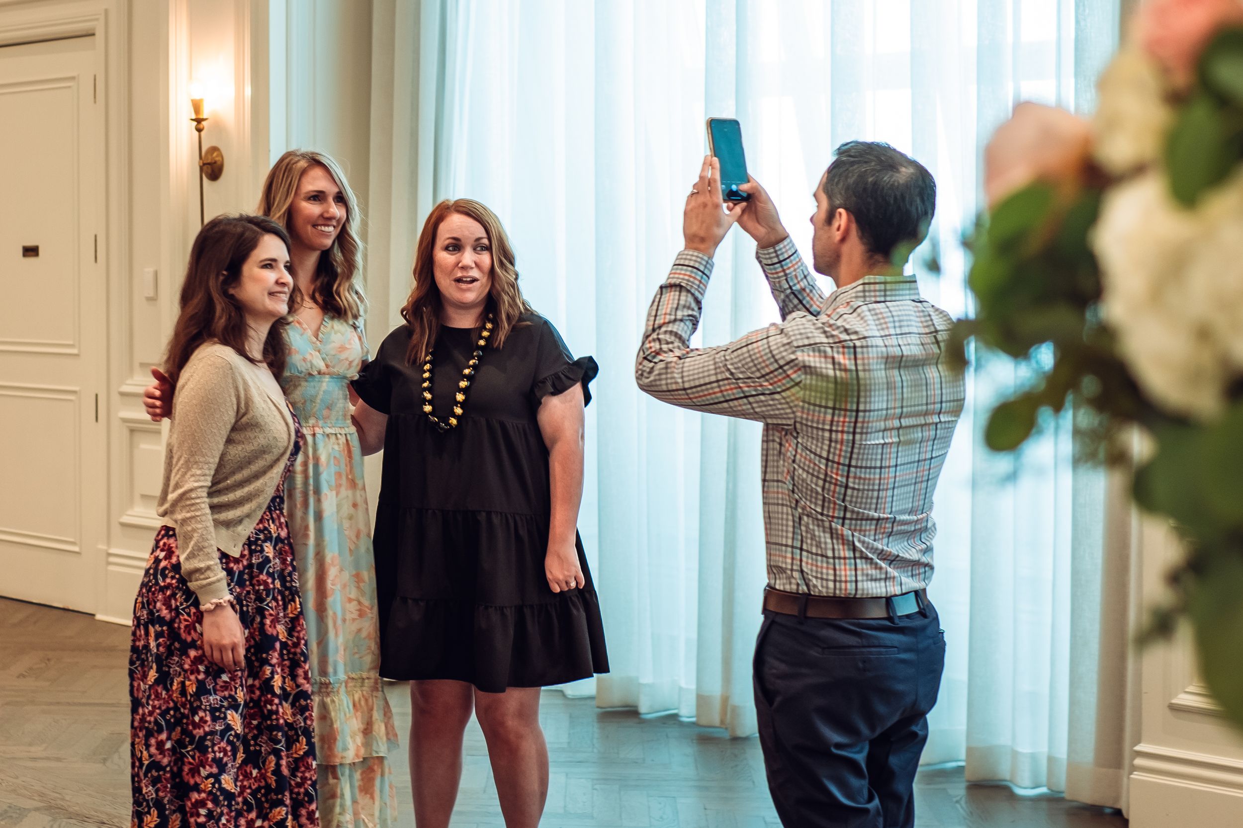 Group of people celebrating and taking photos in a bright indoor setting.