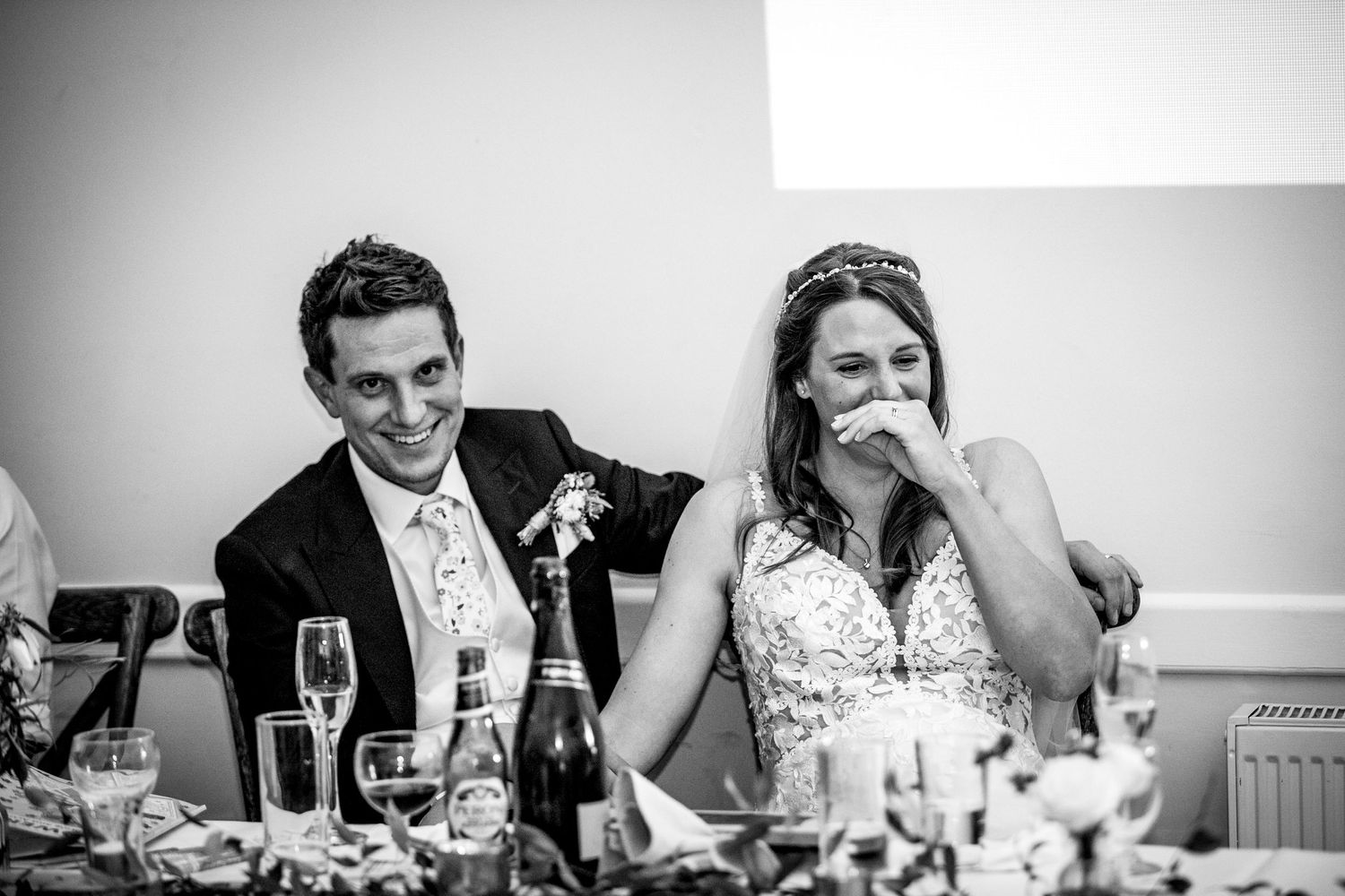 Black and white candid shot of emotional reactions during wedding reception speeches.