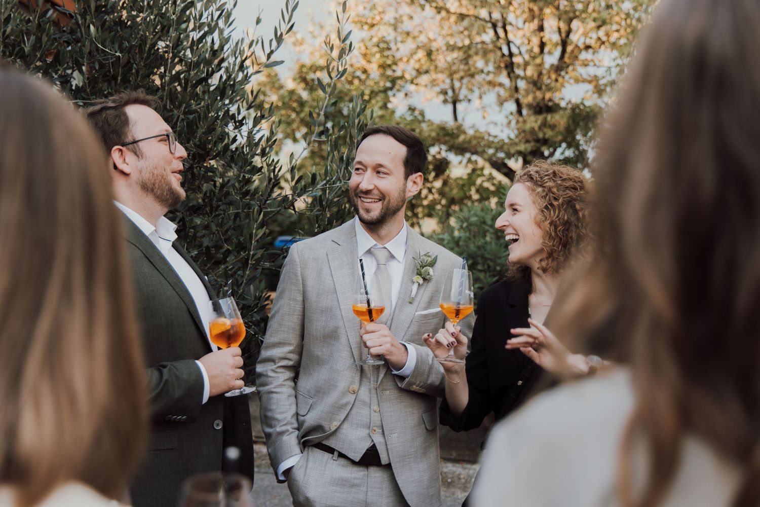 Wedding guests enjoying drinks and conversation in an outdoor garden setting.
