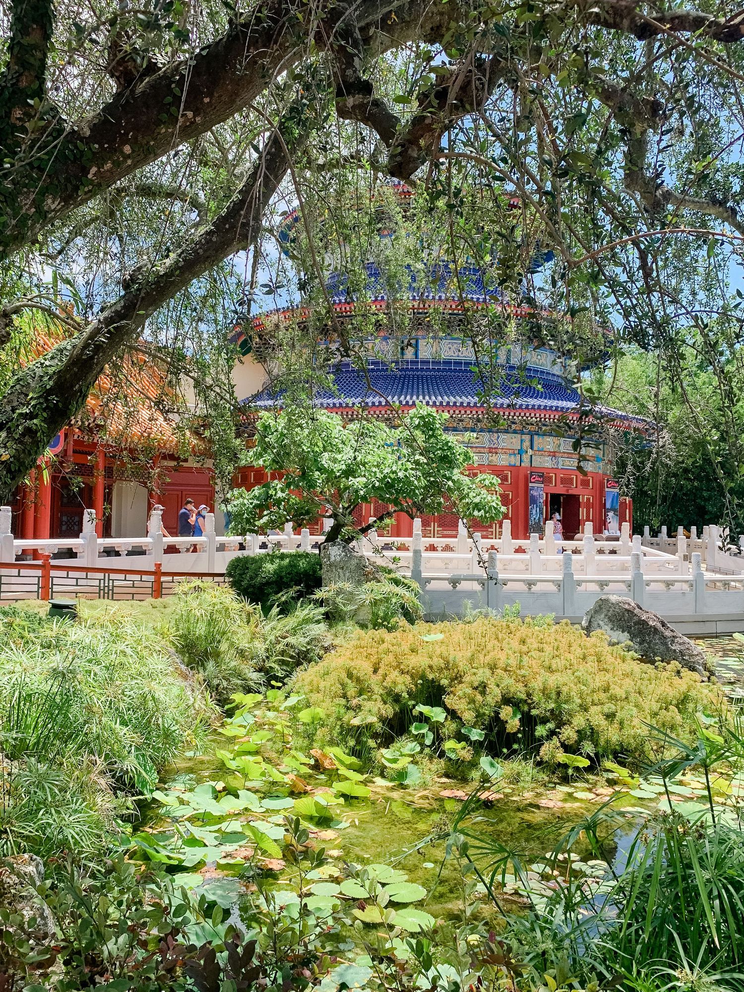 Temple of Heaven replica surrounded by lush gardens and lily ponds in EPCOT's China pavilion.