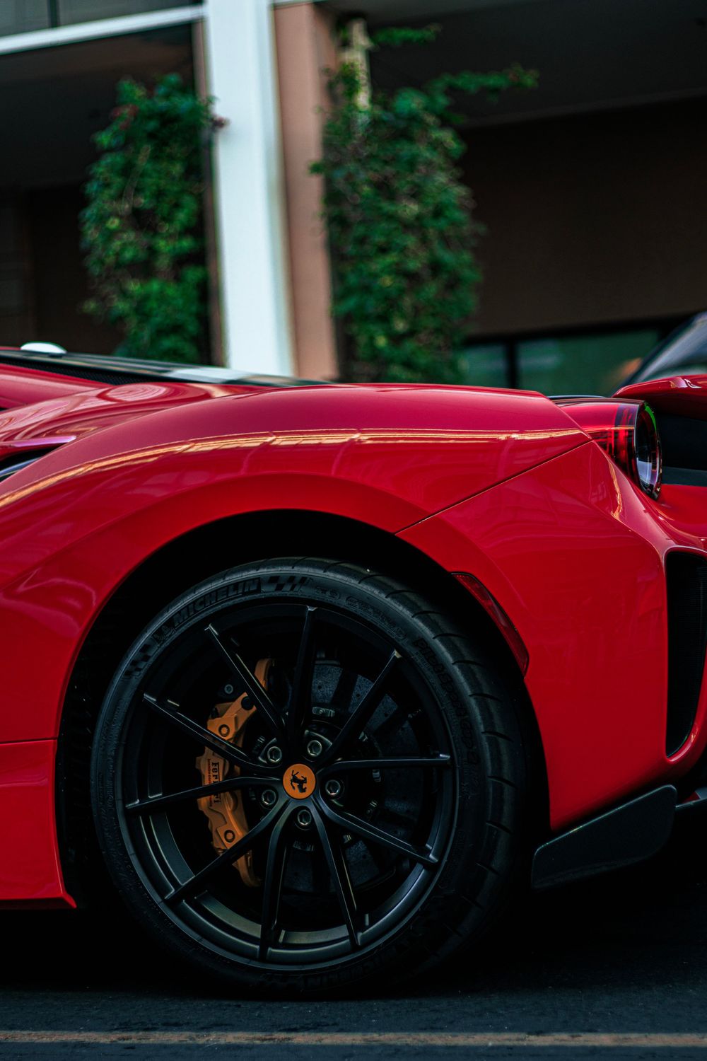 Detail shot of red Ferrari's wheel and brake caliper against dark background.