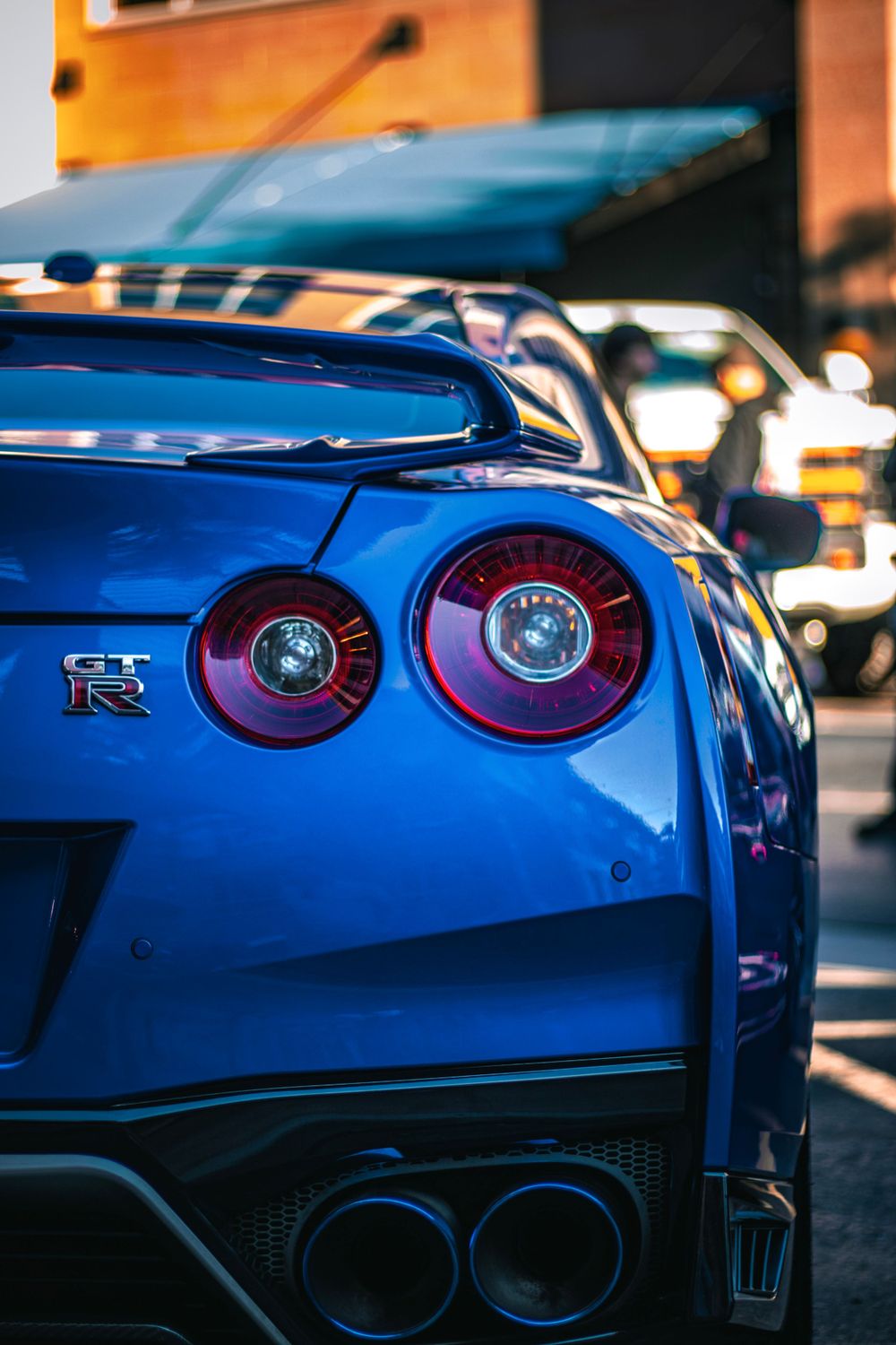 Close-up of blue Nissan GT-R's iconic circular taillights and rear design elements.