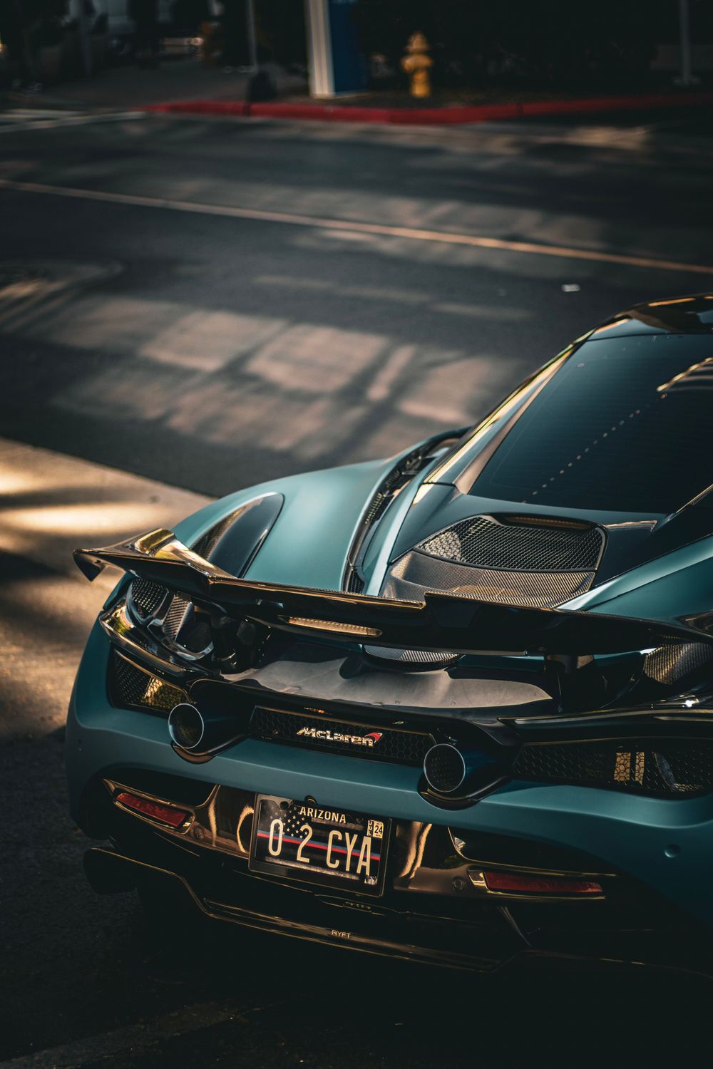 Rear view of a sleek black McLaren supercar with dual exhaust tips captured in dramatic low lighting.