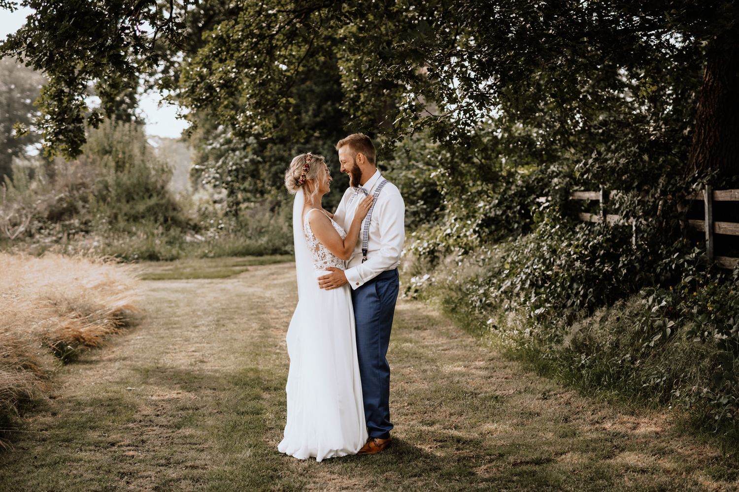 Couple poses together on rustic path with trees and greenery.