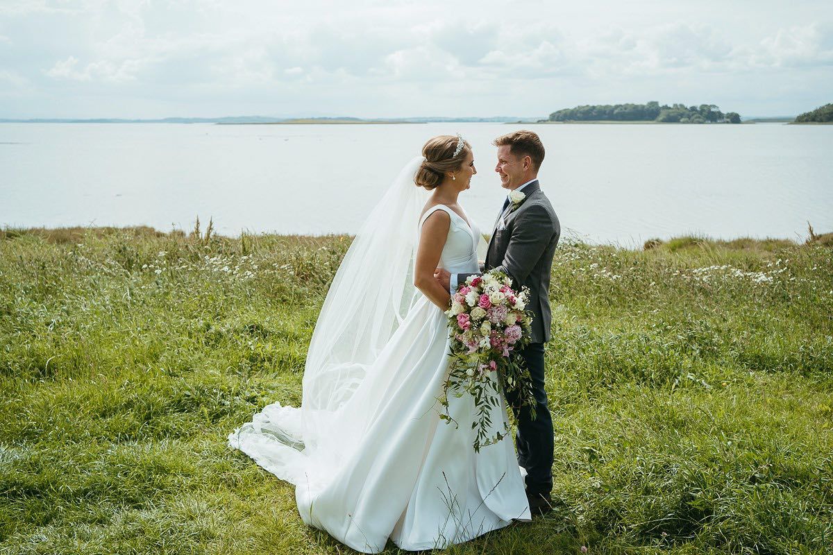 A wedding photoshoot in a scenic coastal meadow with white dress flowing in the breeze.