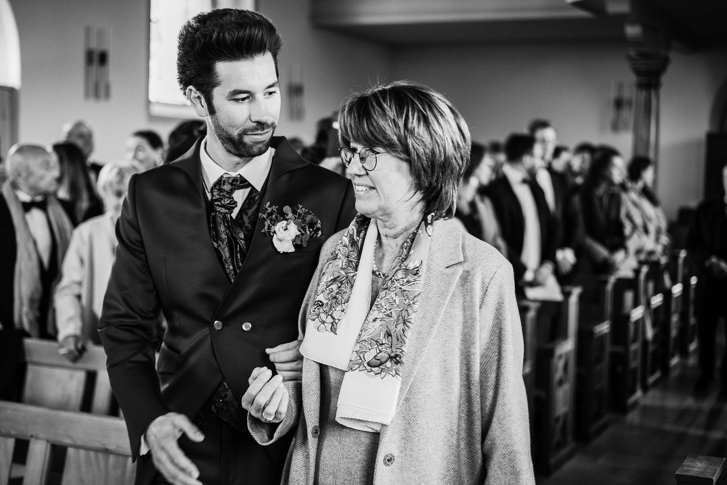 TLOOK photographe de mariage de style documentaire, aux portes des iris cérémonie à l'église le marié entre au bras de sa maman