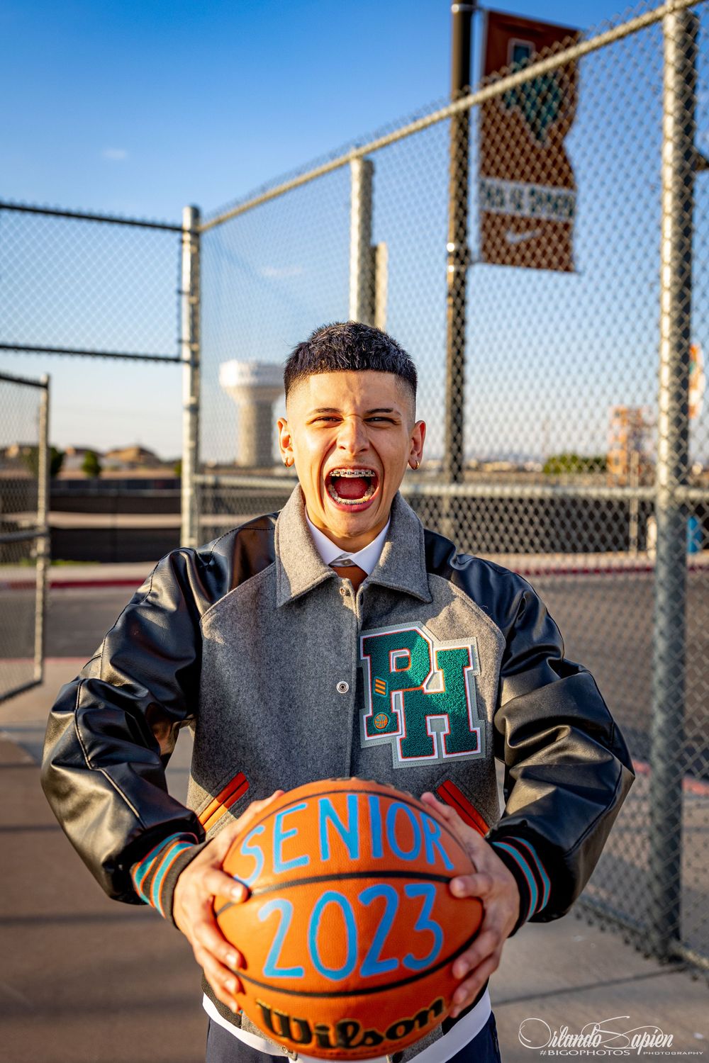Student athlete in letterman jacket poses with basketball showing class year.
