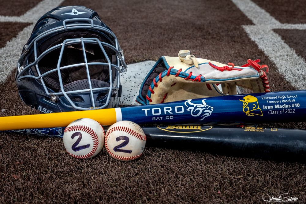 Baseball equipment including helmets, bats, and gloves arranged on a field.