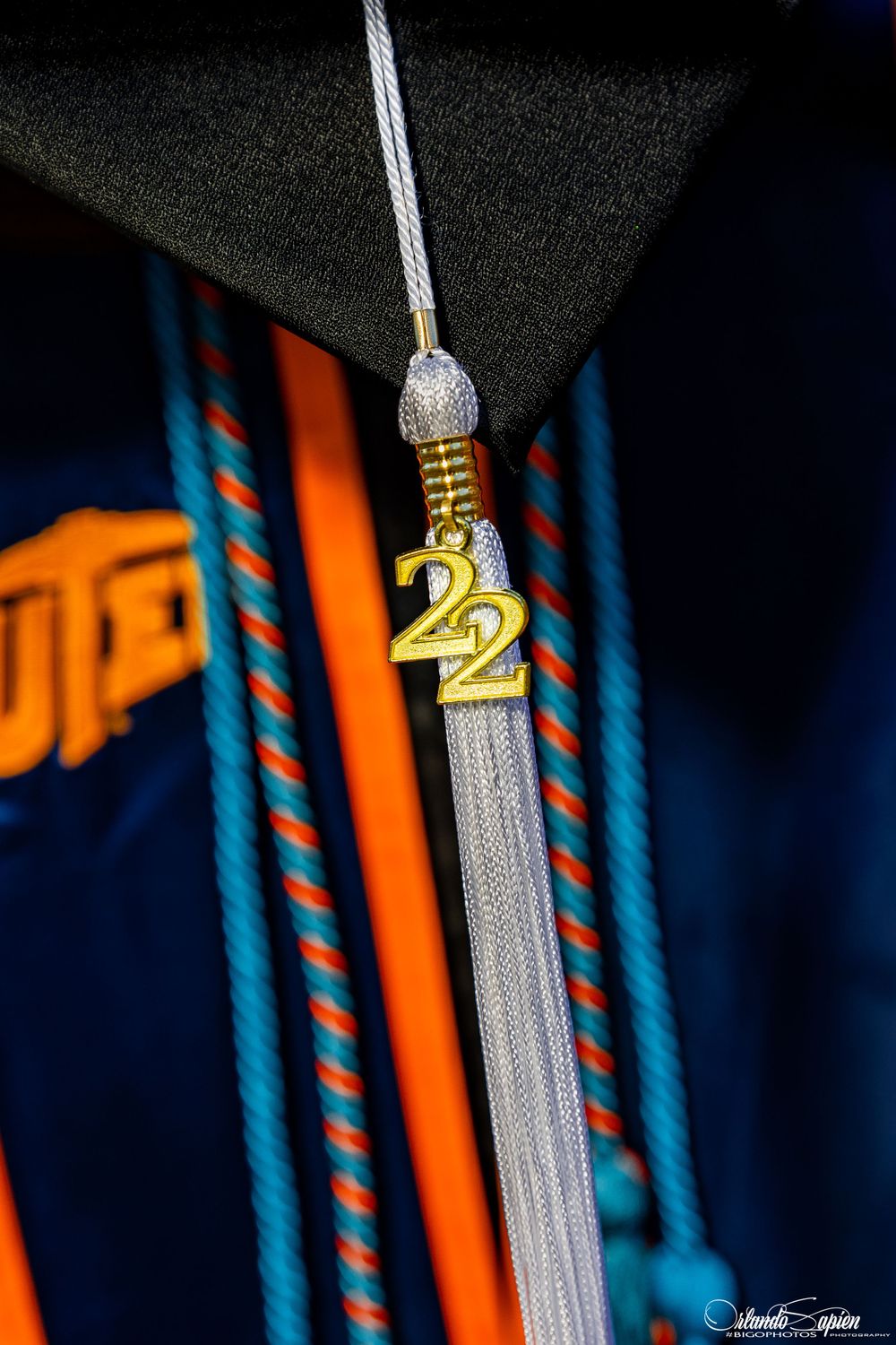 Close-up of silver graduation tassel with '22' charm against dark background.