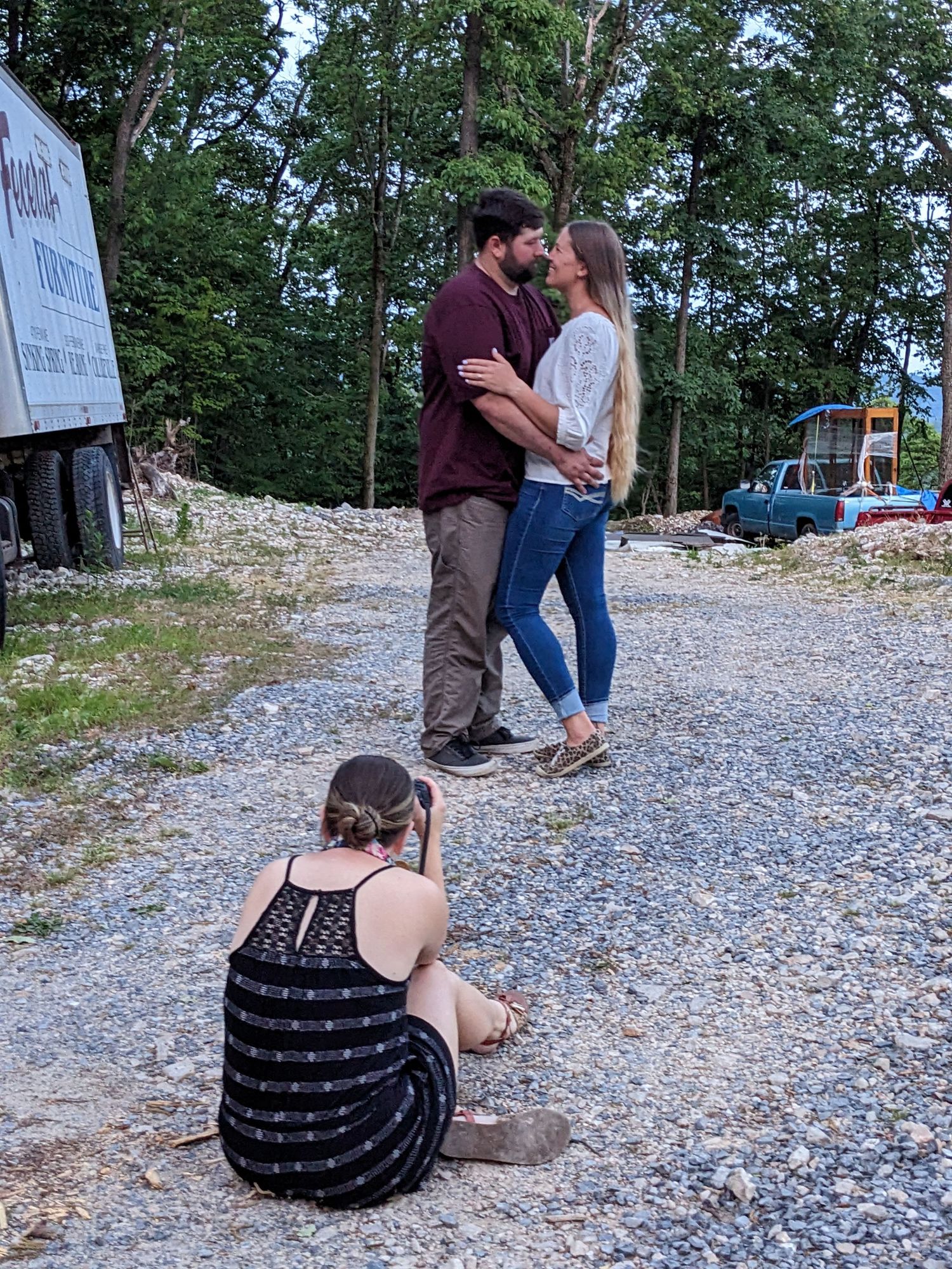 Photographer captures romantic couple moment on gravel path near trees.