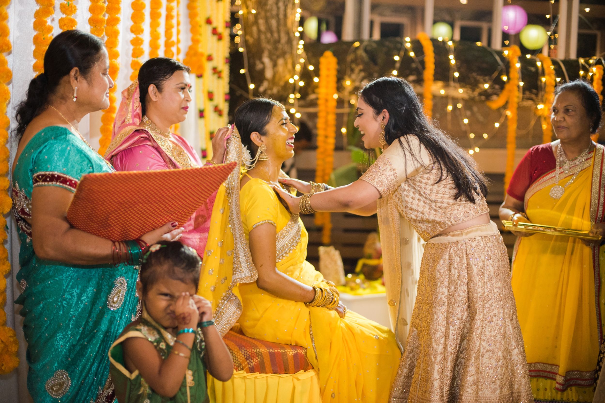Traditional Indian wedding ceremony with guests in colorful saris and decorative backdrop.