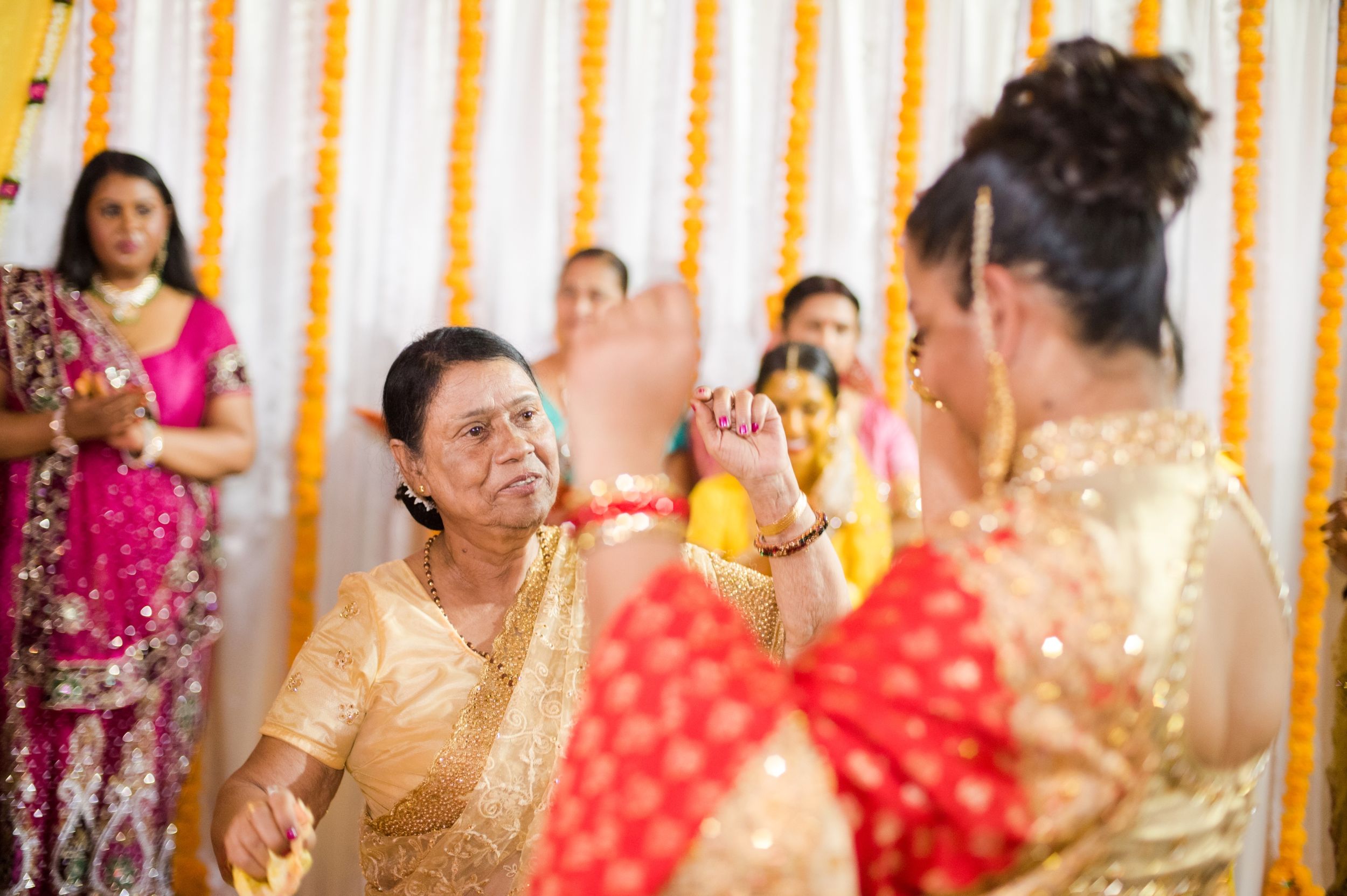 Traditional dance celebration with performers in vibrant saris against yellow and white backdrop.