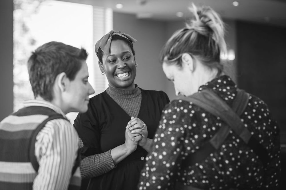Candid moment of three people sharing laughter during a social event.