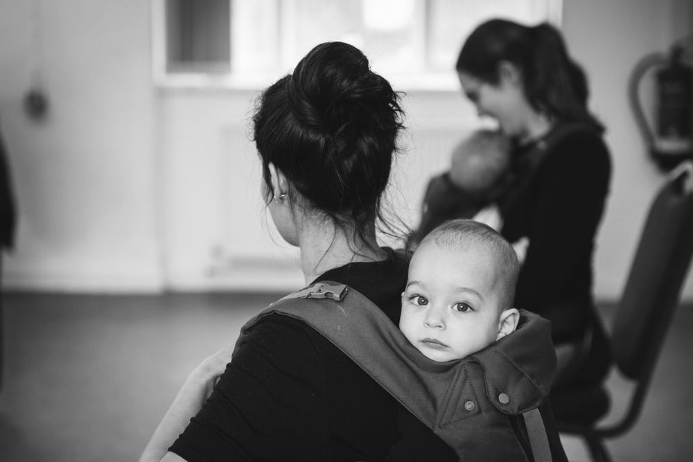 Black and white image of baby peering over adult's shoulder.