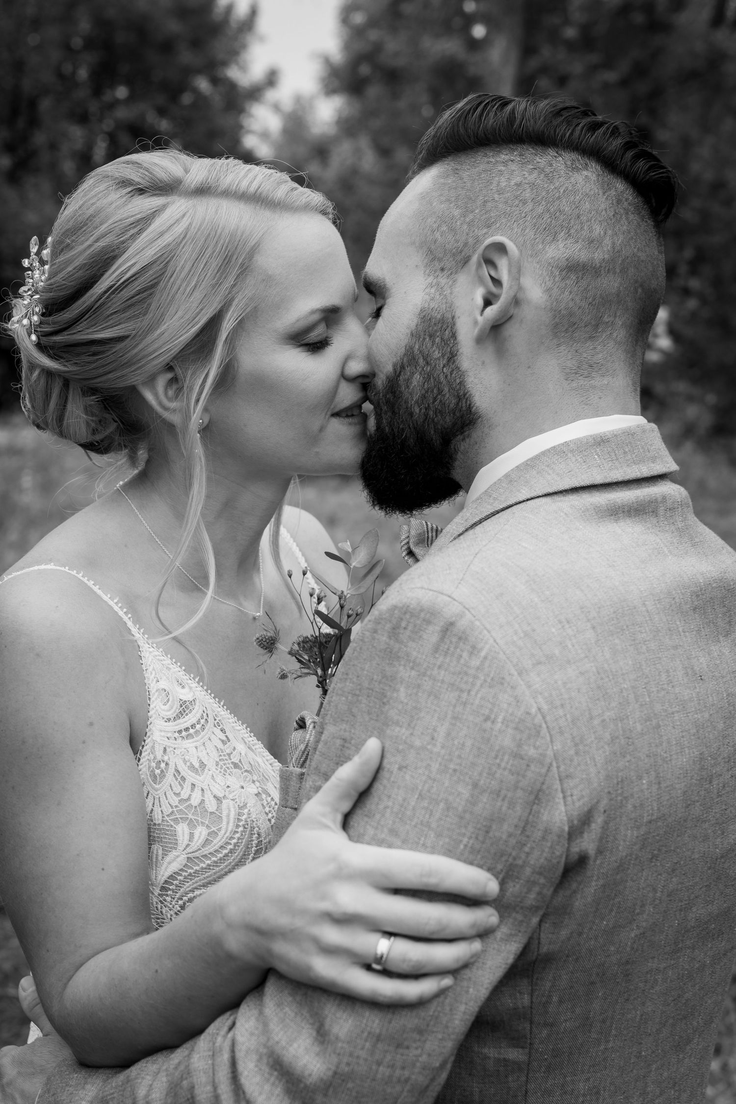 Romantisches Schwarz-Weiß-Hochzeitsporträt von Jungvermählten, die einen intimen Moment im Freien teilen.