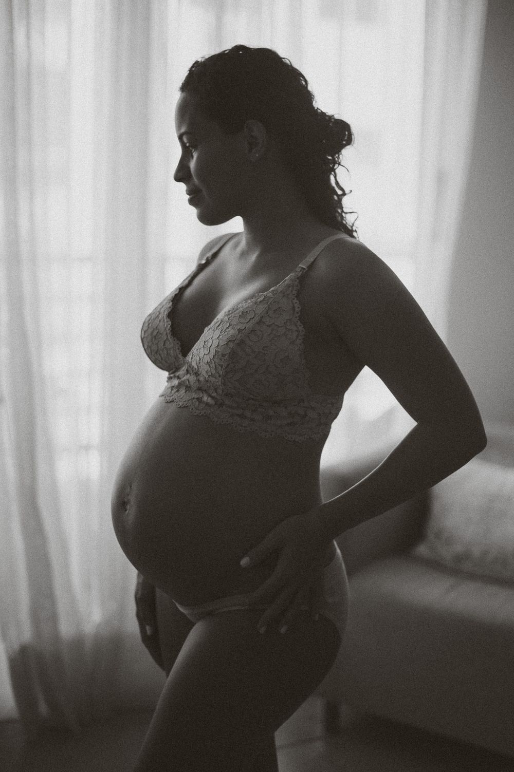 Artistic black and white silhouette of an expectant mother in lingerie.