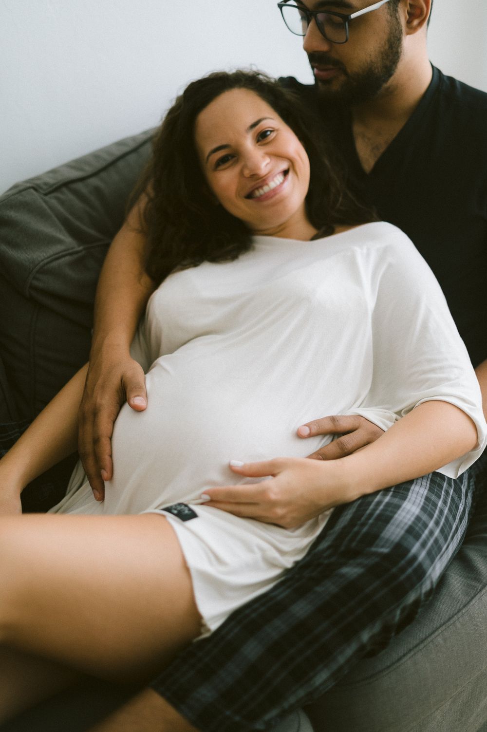A relaxed maternity moment captured on a grey couch.