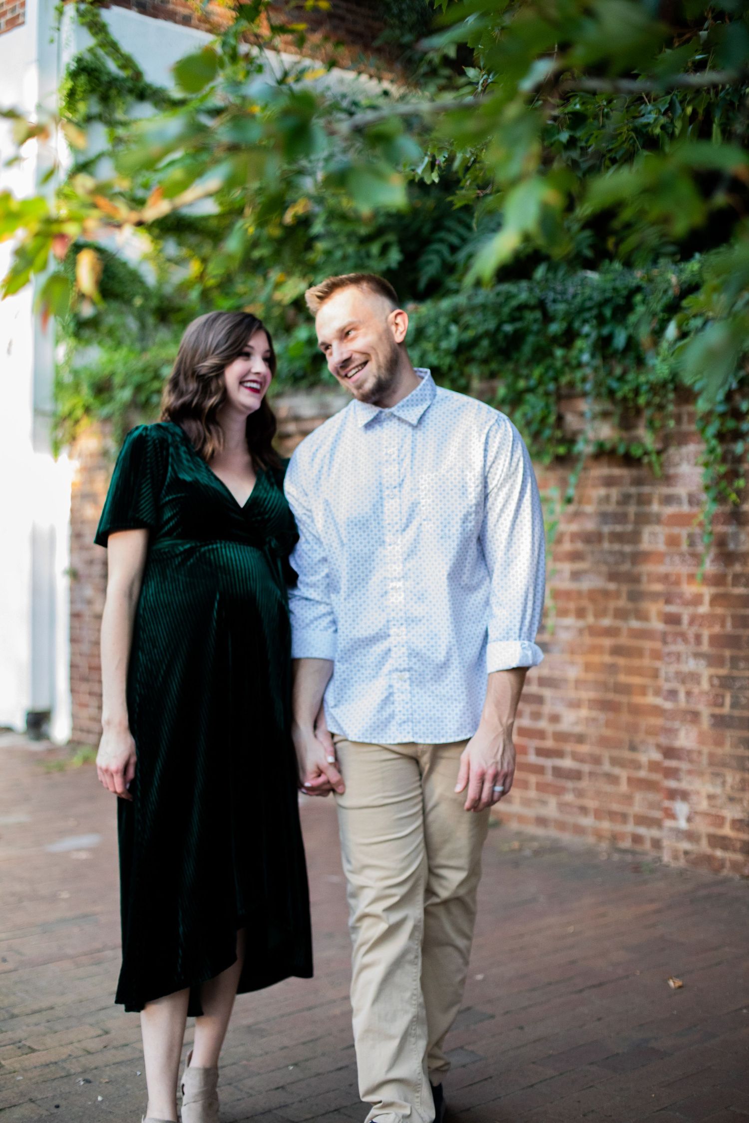 A couple shares a joyful moment together against a brick wall backdrop in an outdoor setting.