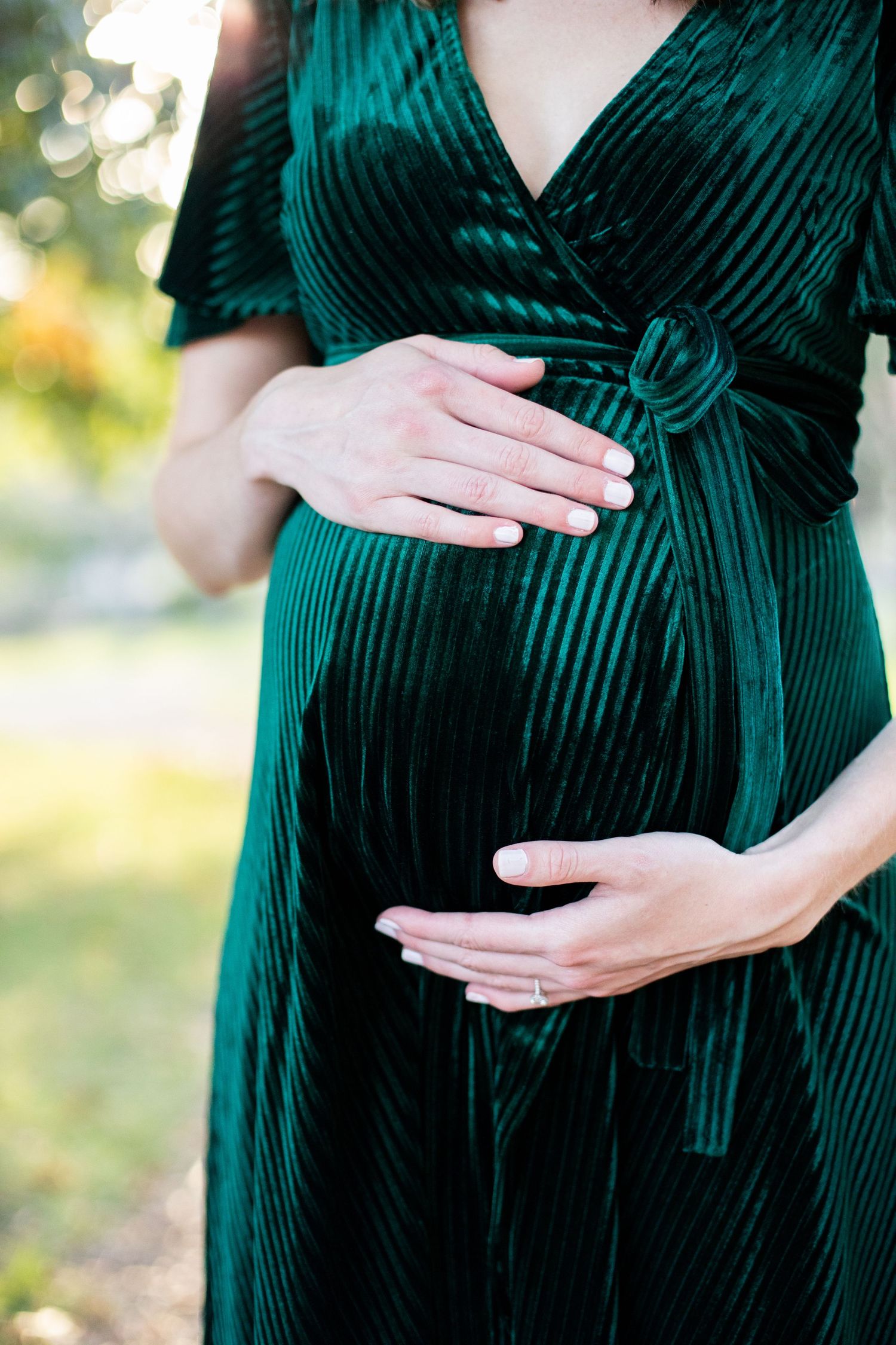 Close-up shots of a green velvet maternity dress showing a growing baby bump.