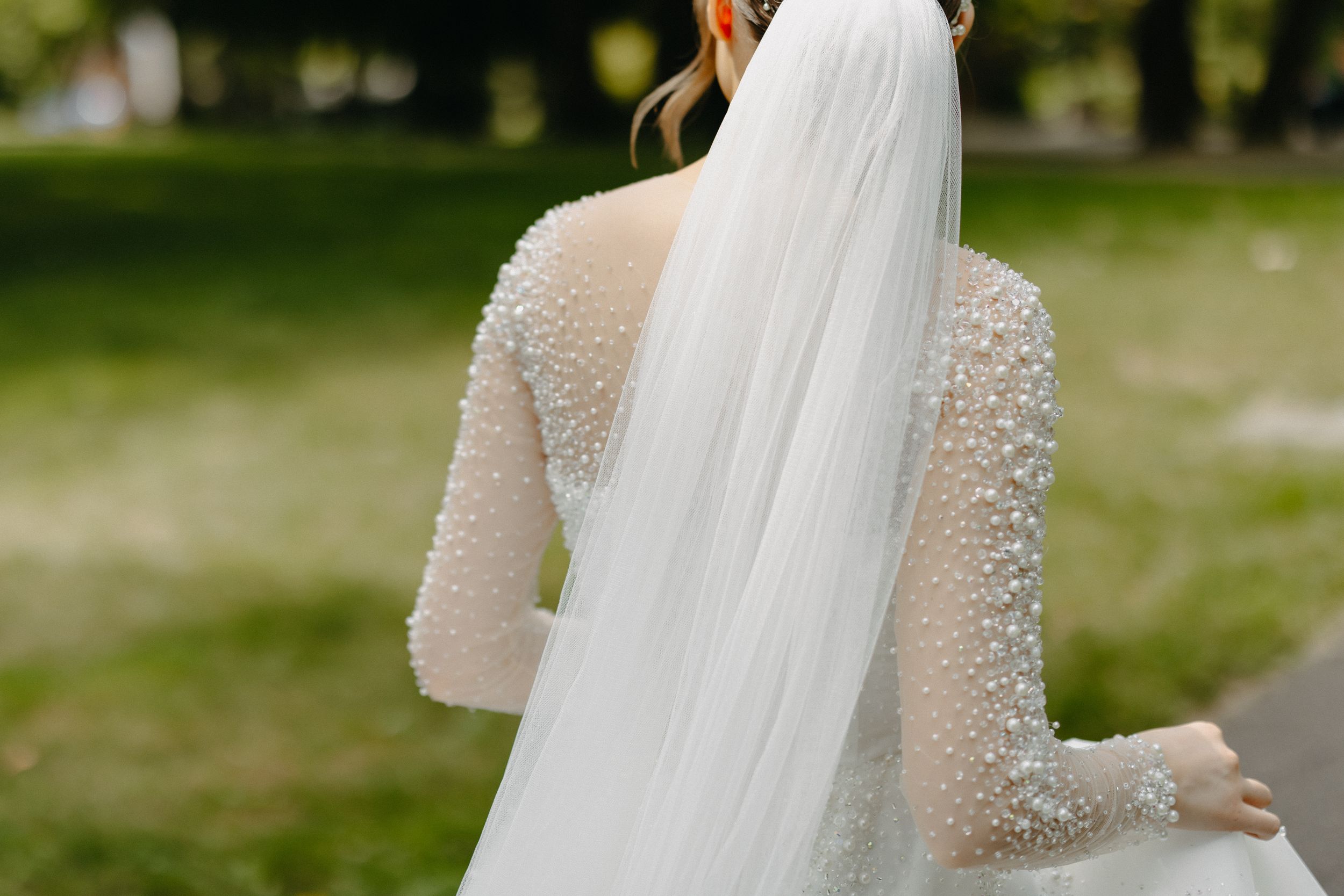 Back view of a bride's wedding dress with detailed lace sleeves and flowing veil.