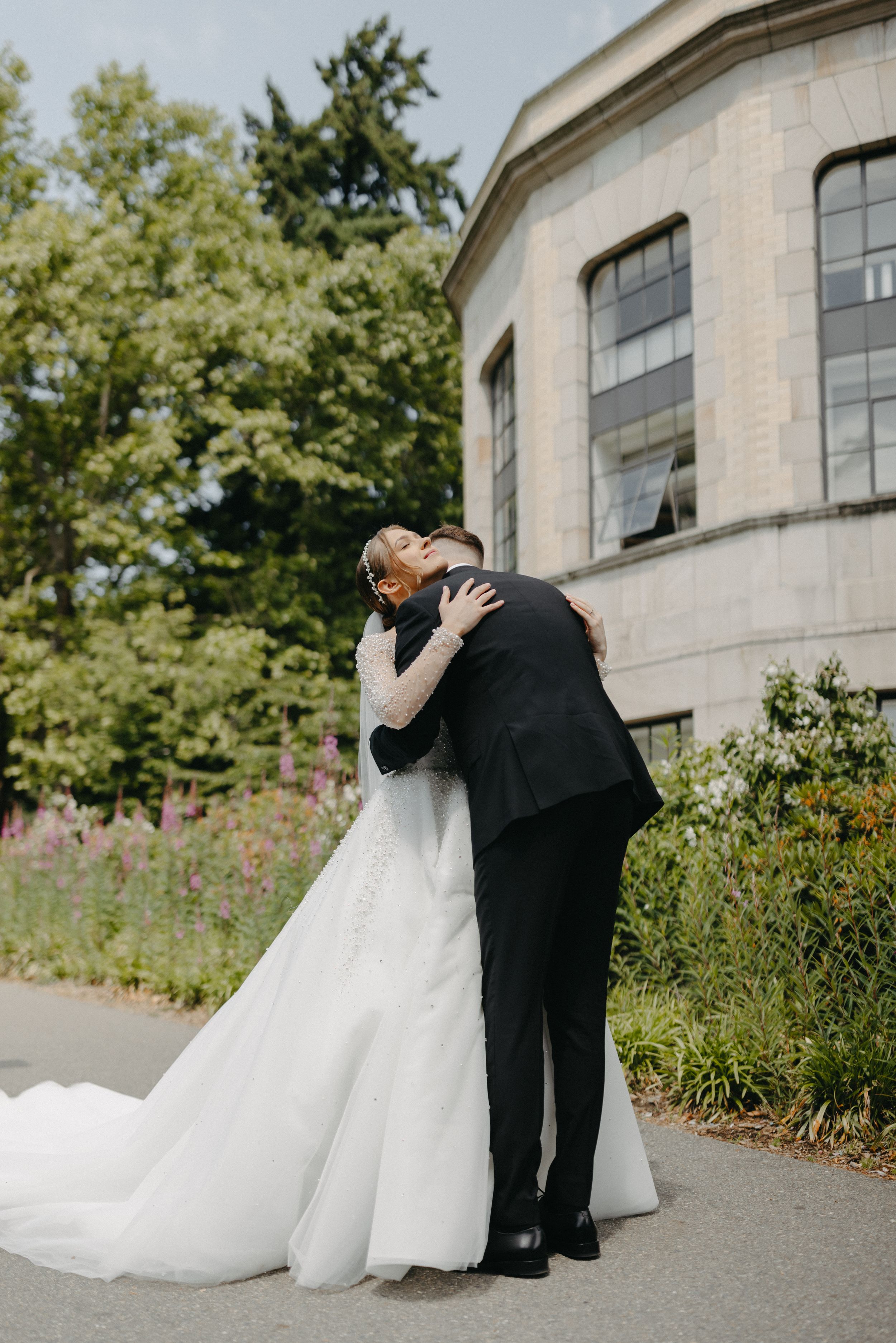 A tender embrace between newlyweds on a garden path.