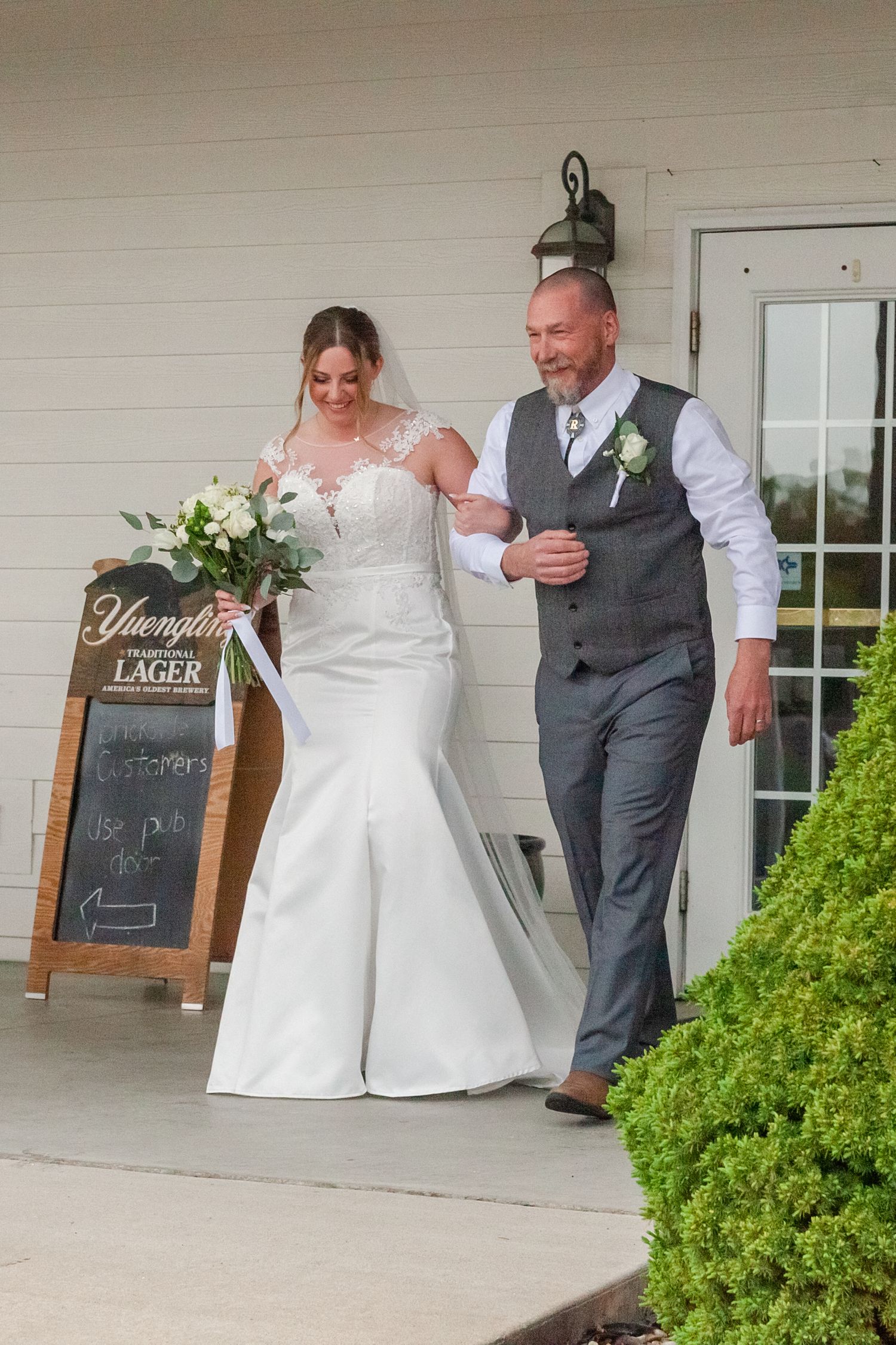A couple shares their first dance moment on a covered porch with chalkboard signs visible.