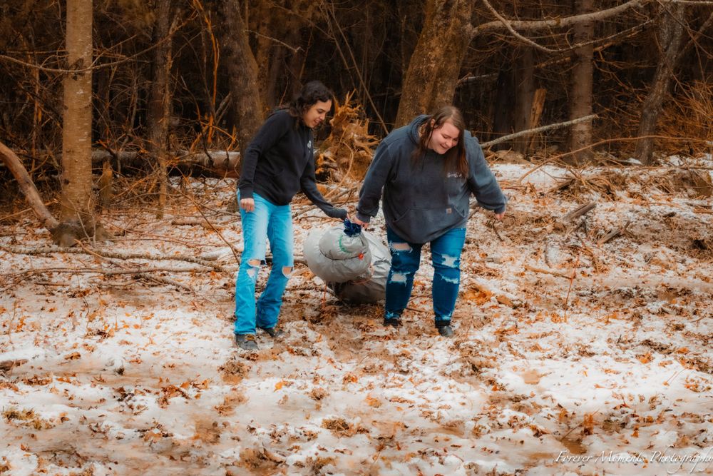 People playing and walking through a snow-dusted forest in winter.