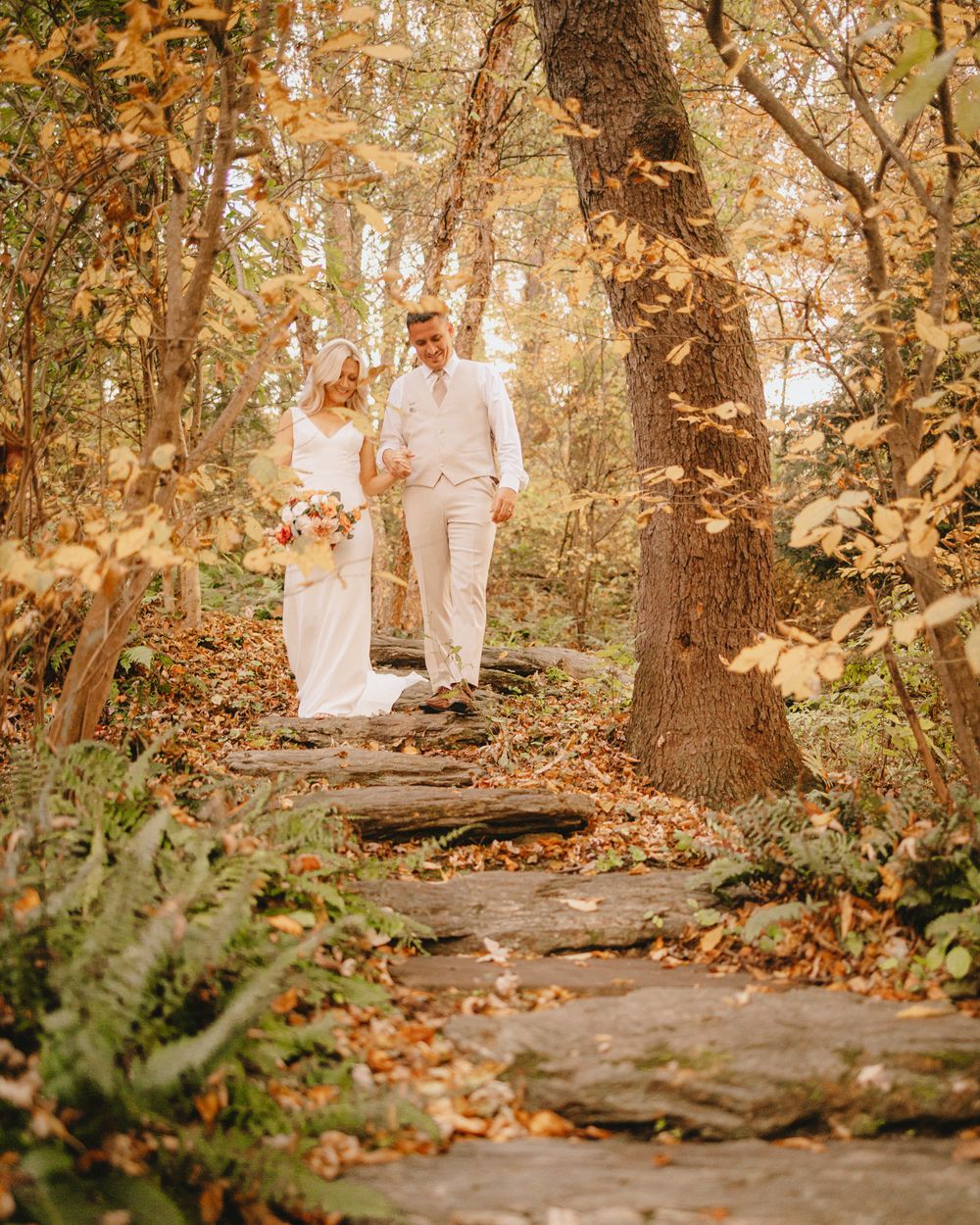 bride and groom walk side by side down stone steps in autumn forrest