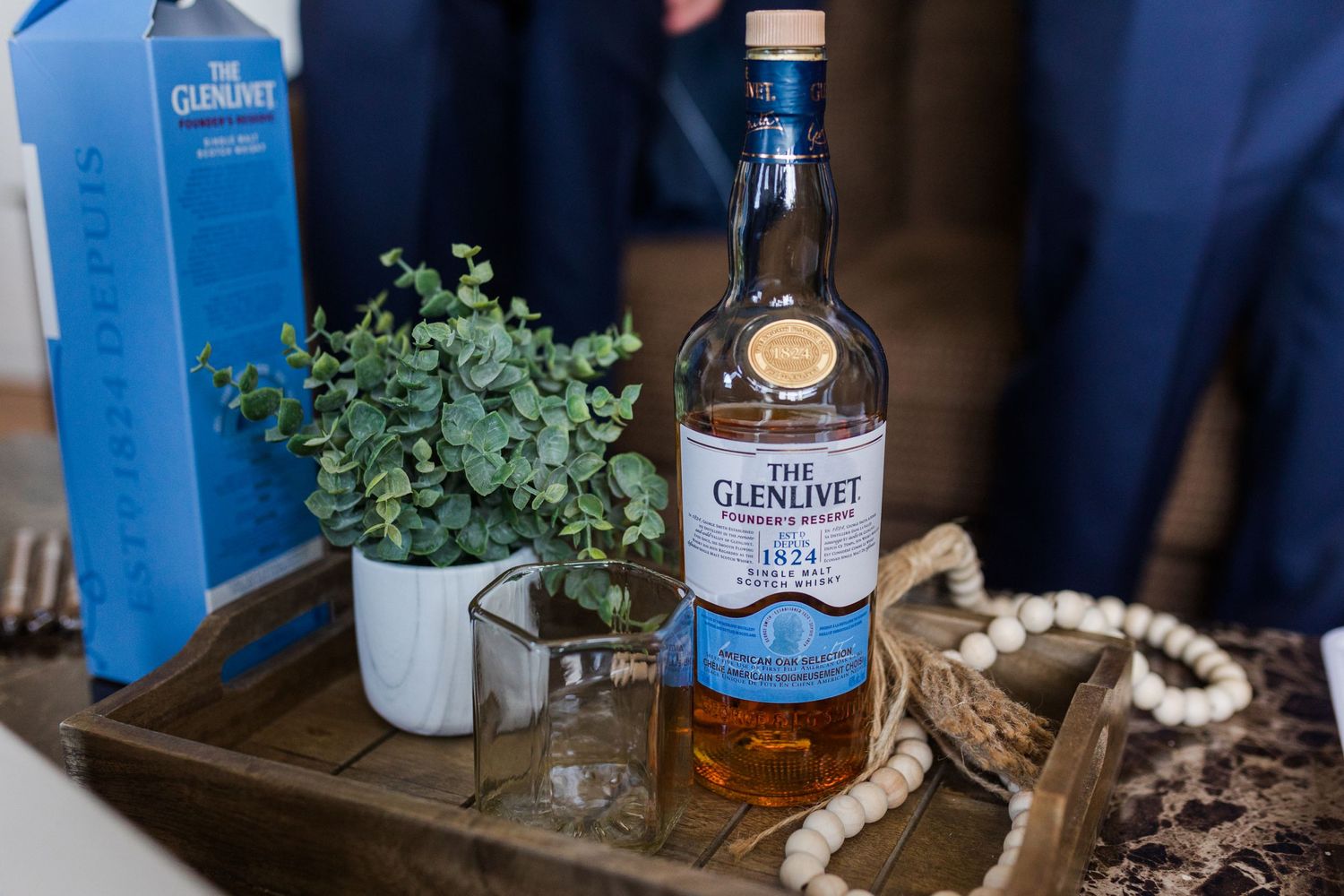 Blue glass bottles and eucalyptus decorate a rustic wooden surface at an event.