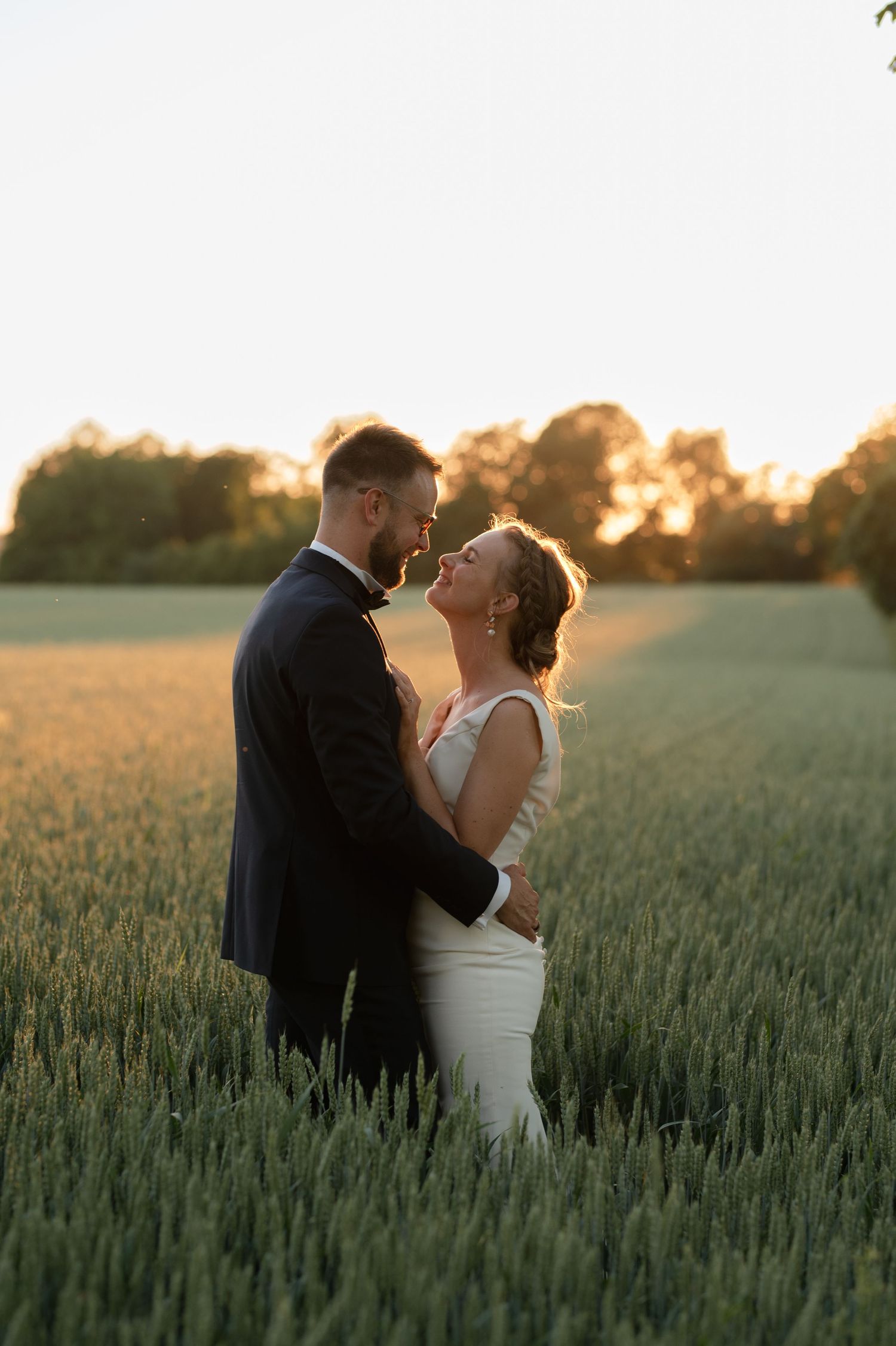 Newlyweds embracing in a wheat field during golden hour.