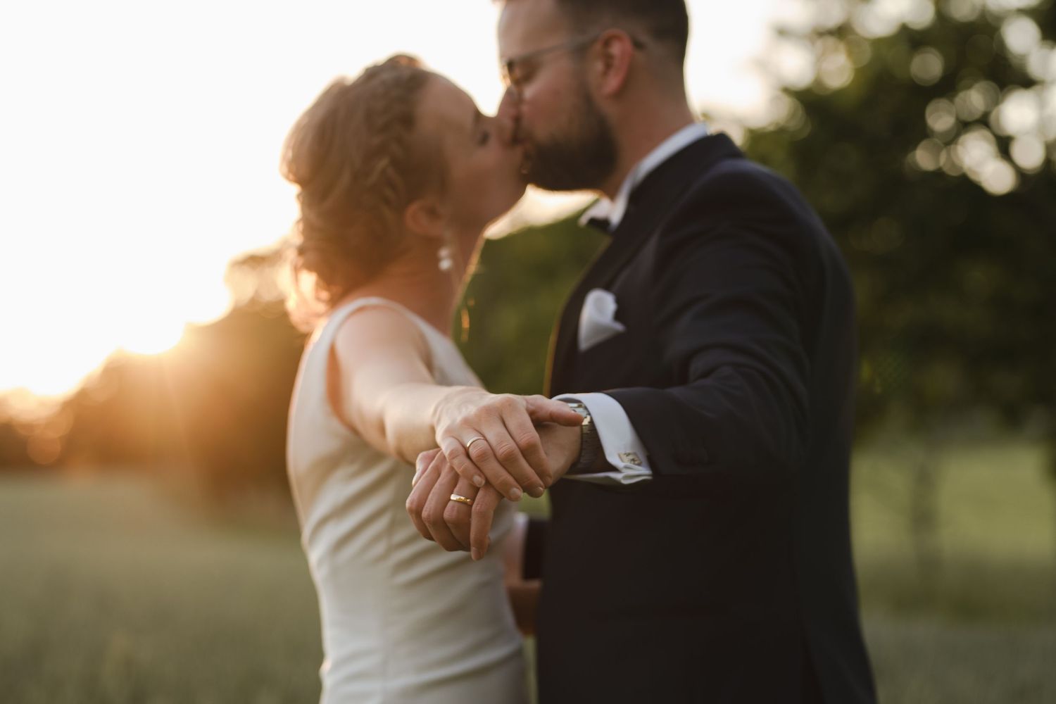 Intimate sunset moment between newlyweds in a summer field.