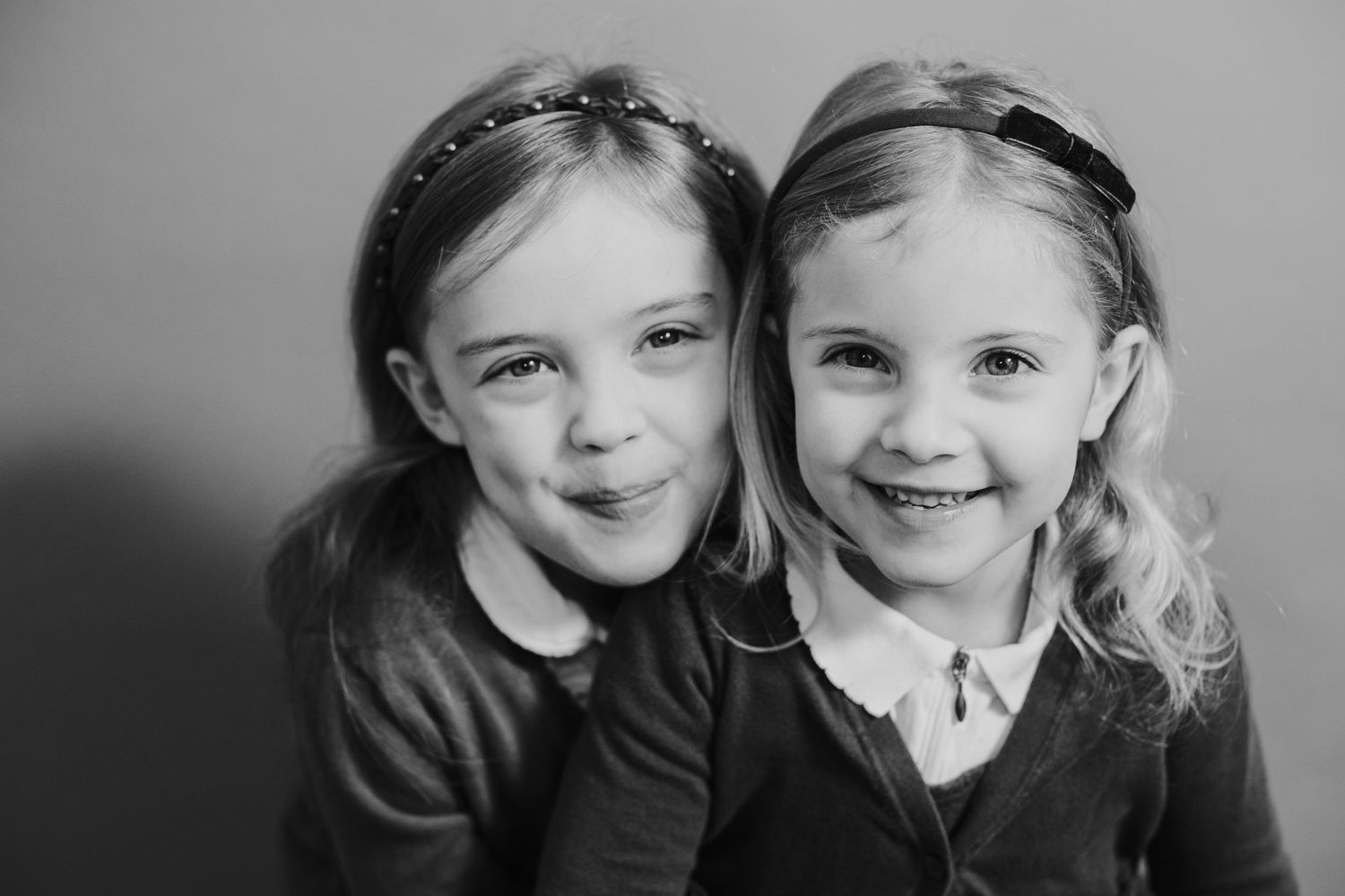 Black and white studio portrait of two young children smiling together.