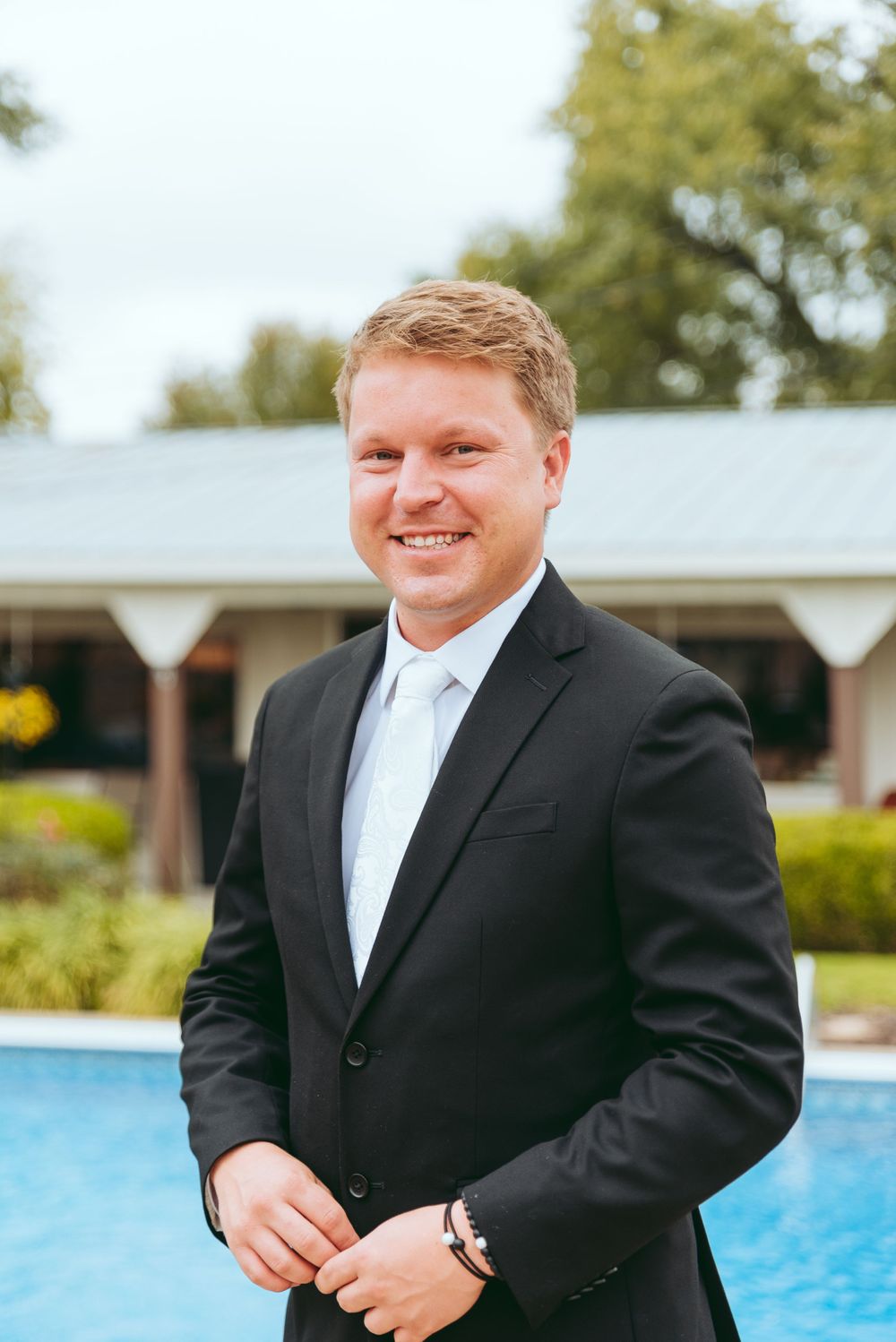 Groom poses for a portrait near the family pool.