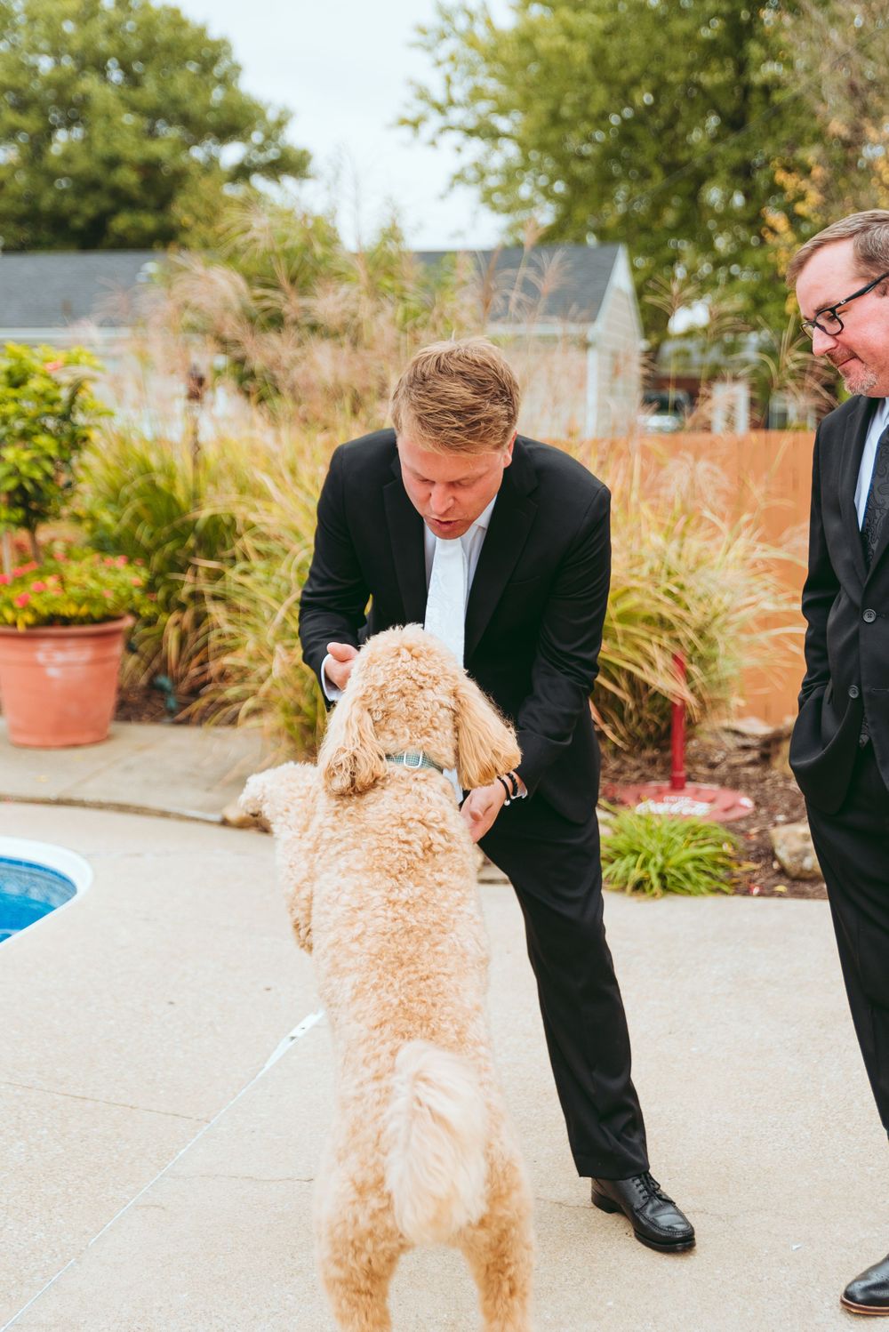 Groom plays with his dog, a golden-doodle.