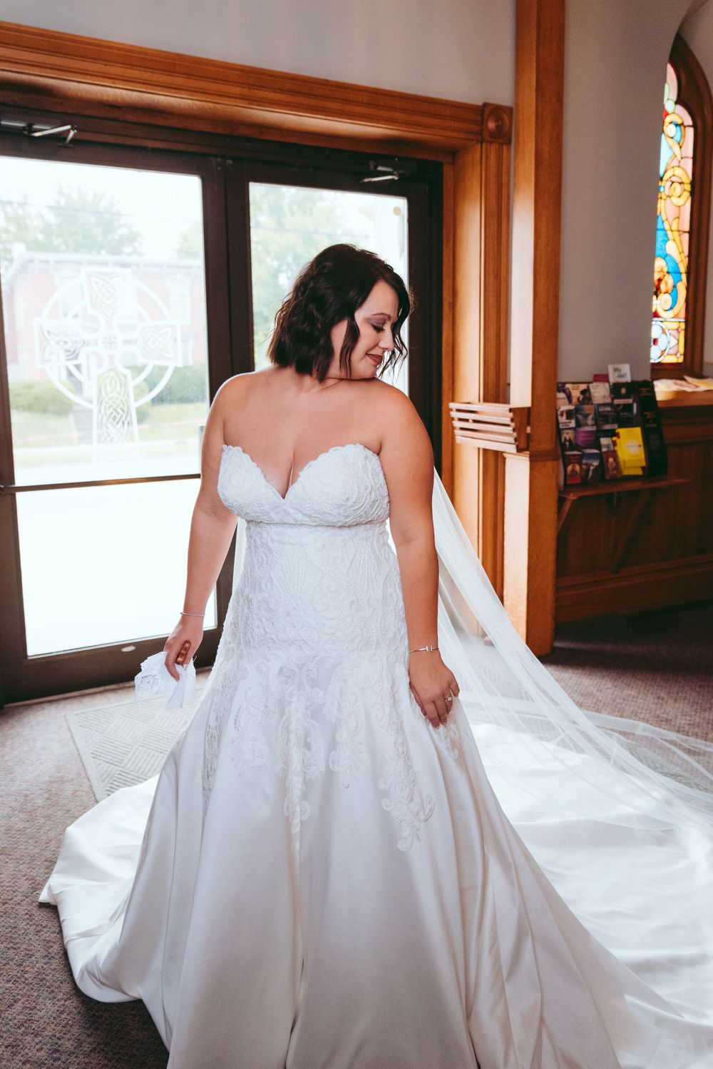 Bride looks over her shoulder in the church foyer.