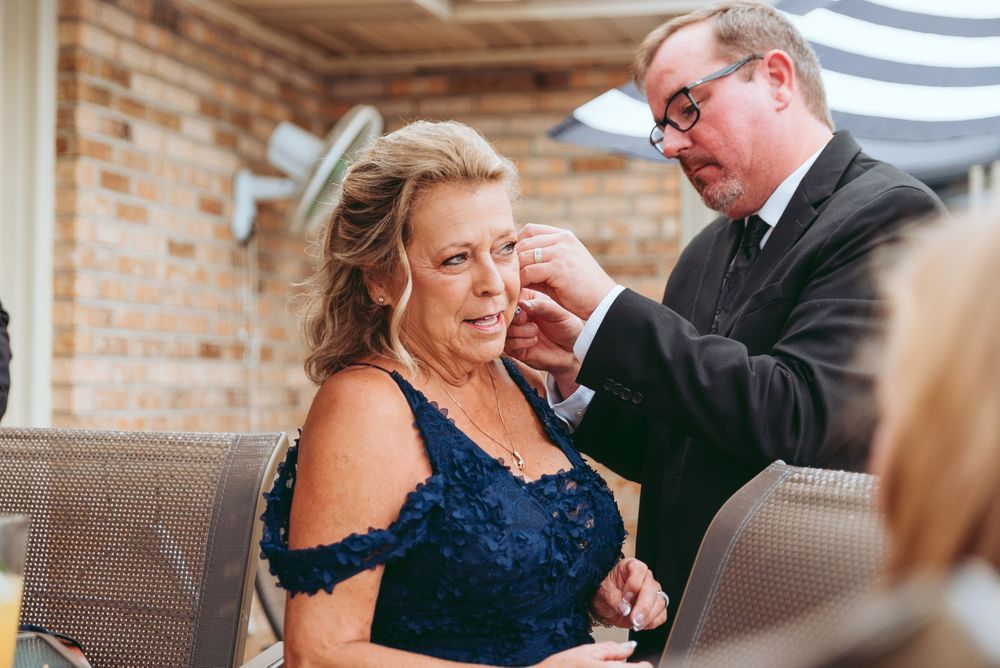 Groom's mother gets help putting her earring on.