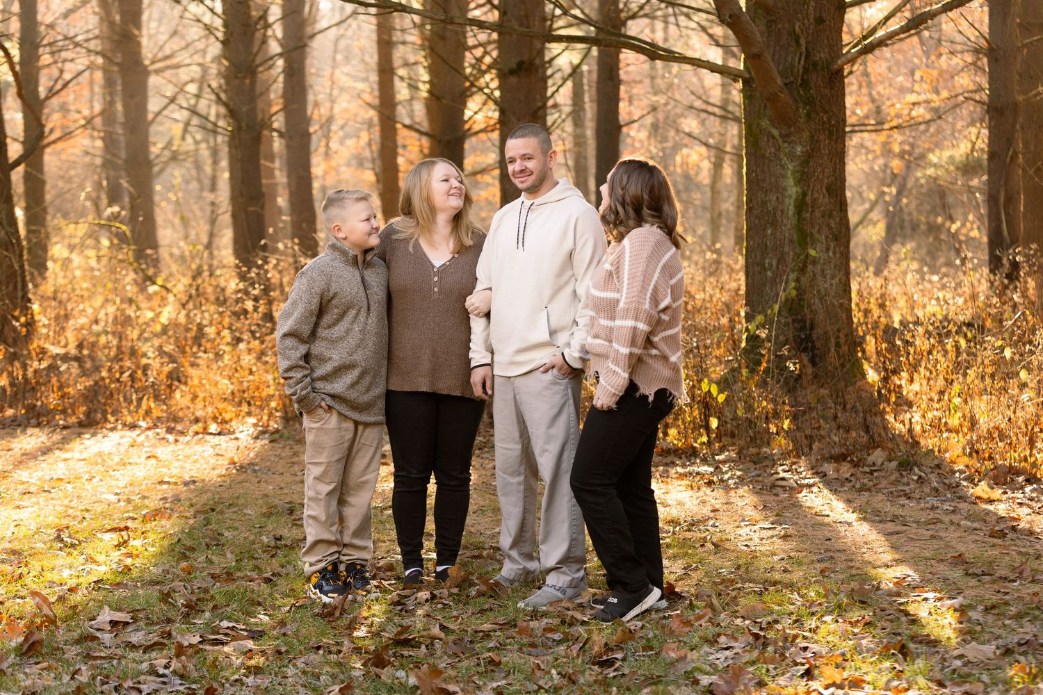 Light streams through a fall forest behind a family of four.