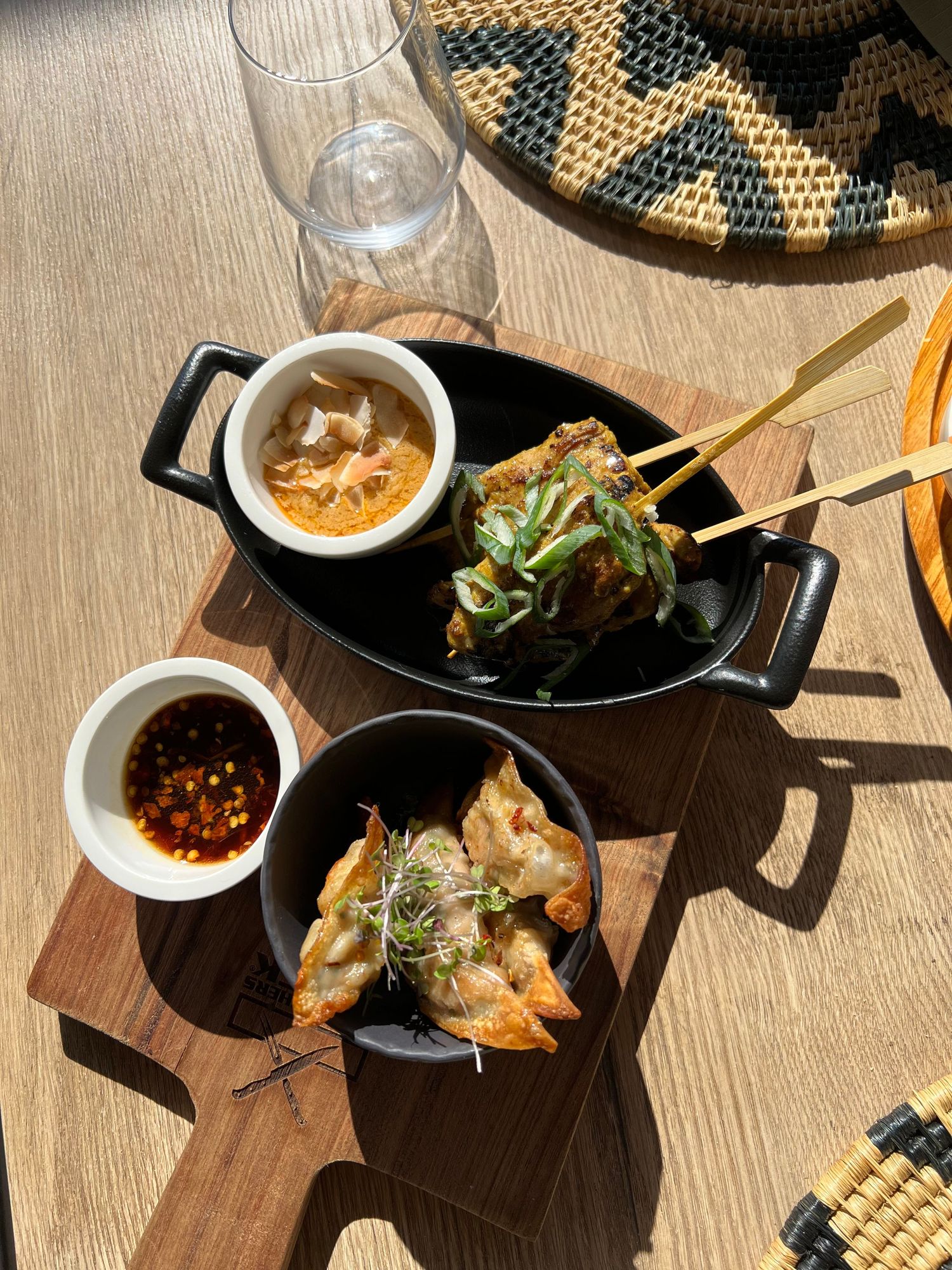 Artfully plated appetizers served on wooden boards with dipping sauces in sunlit setting.
