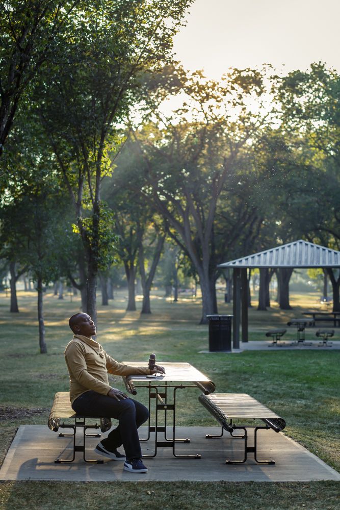 Portrait session for podcast host. He is sitting at a picnic table with the microphone and light rays on him