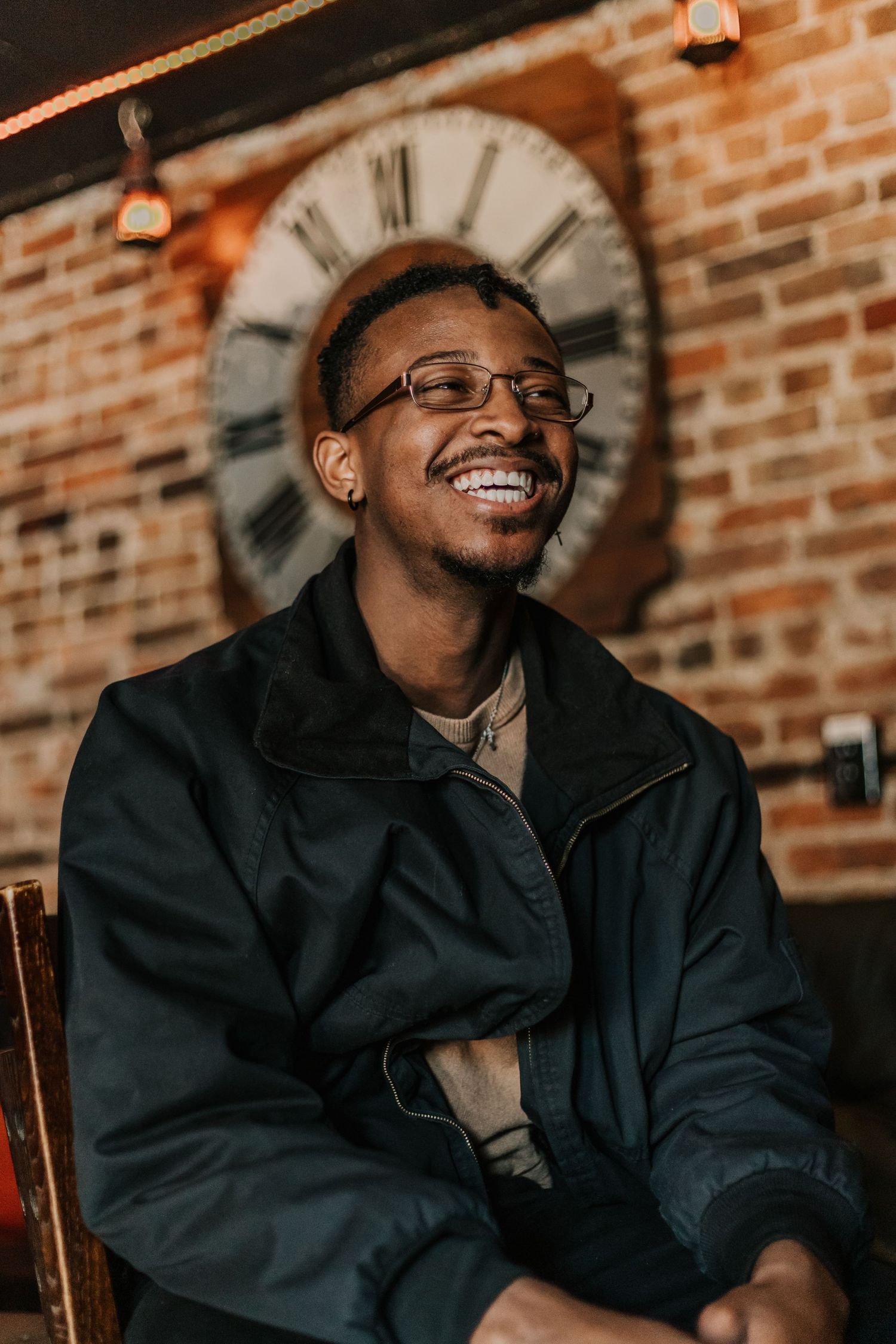 Black man smiling, black joy, brick wall, portrait photography