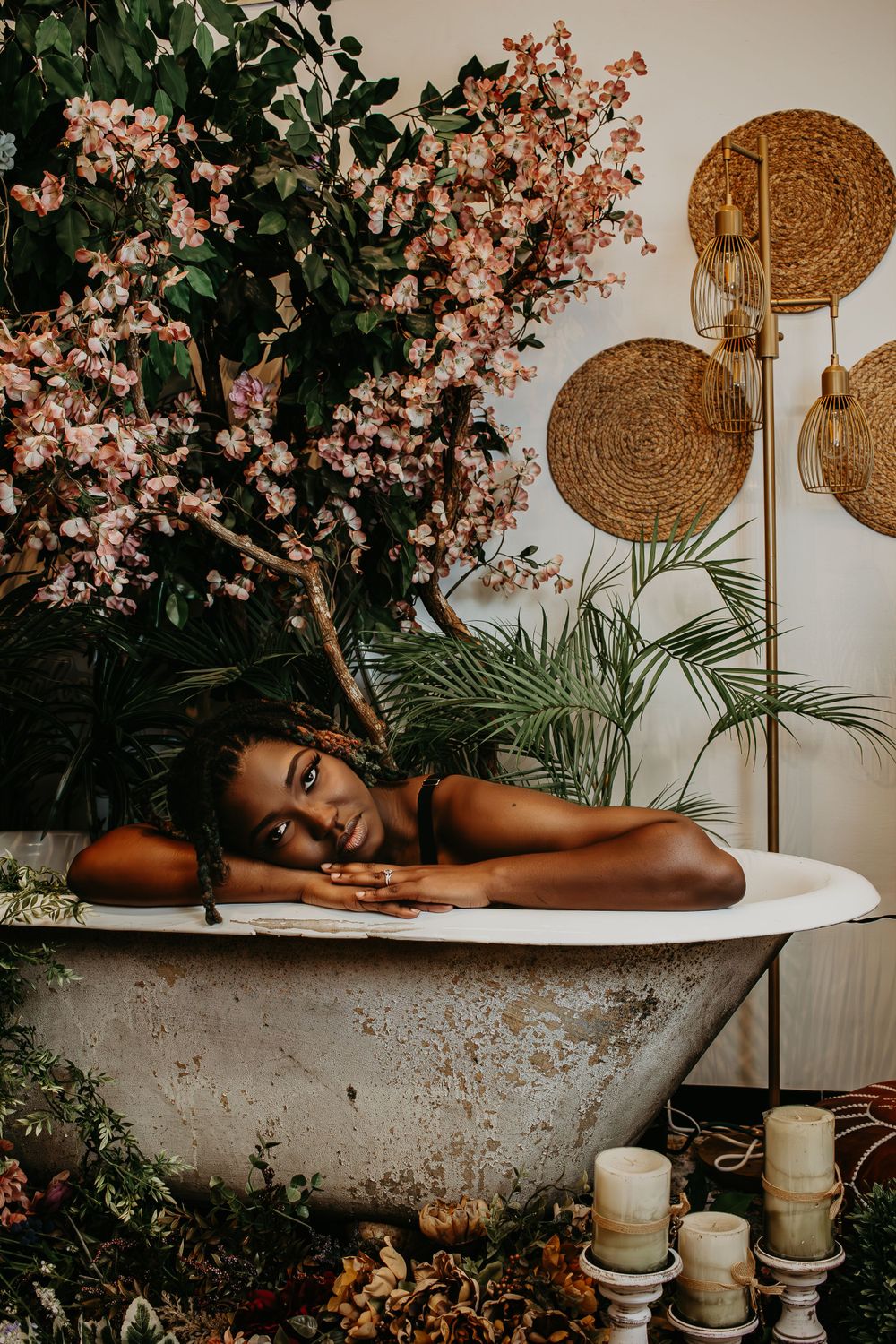 Dreamy bathtub portrait surrounded by cherry blossoms and decorative woven wall hangings.